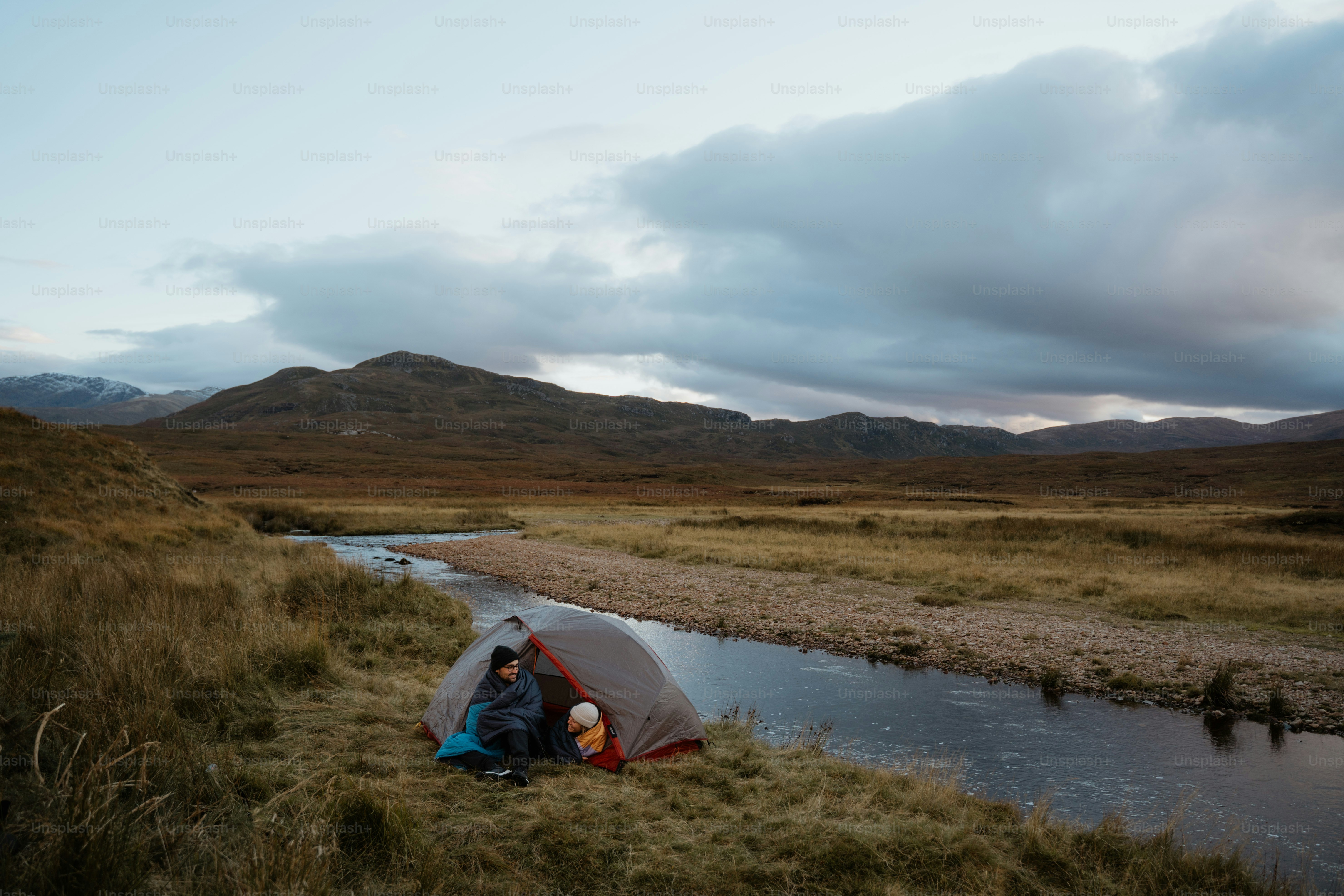 A group of people standing around a tent next to a river