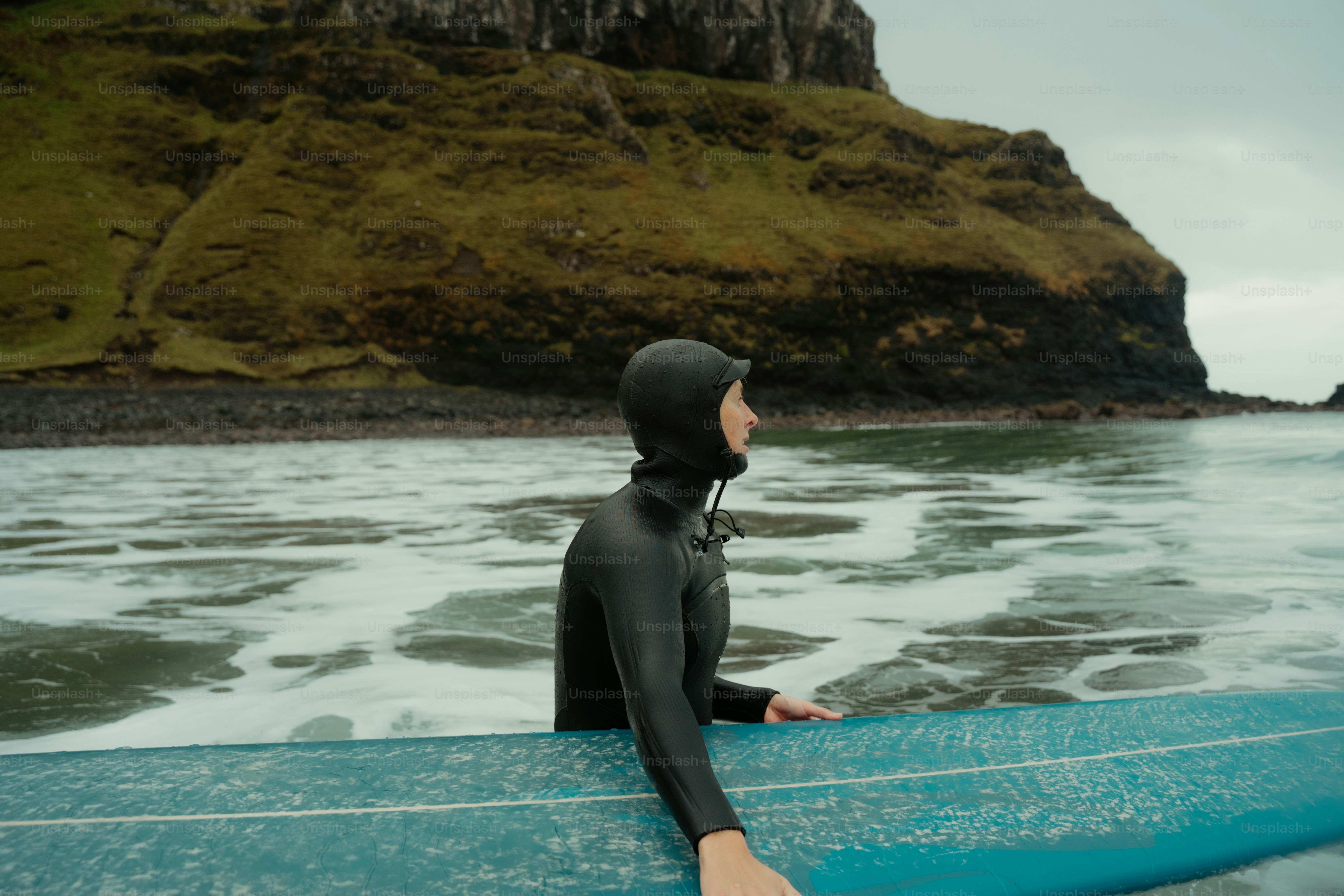 A person in a wet suit sitting on a surfboard