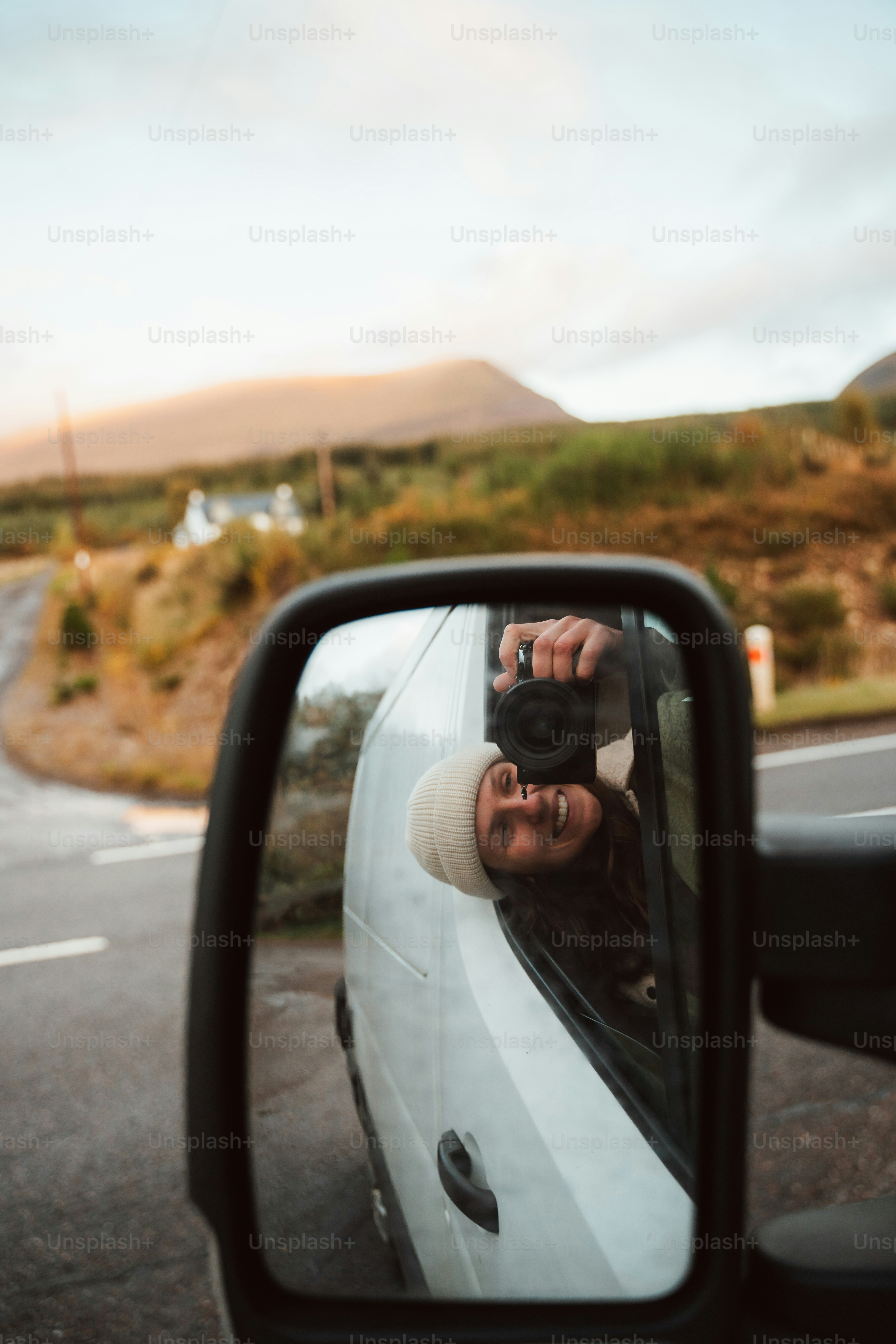 Eine Frau, die ein Foto von sich im Seitenspiegel eines Autos macht