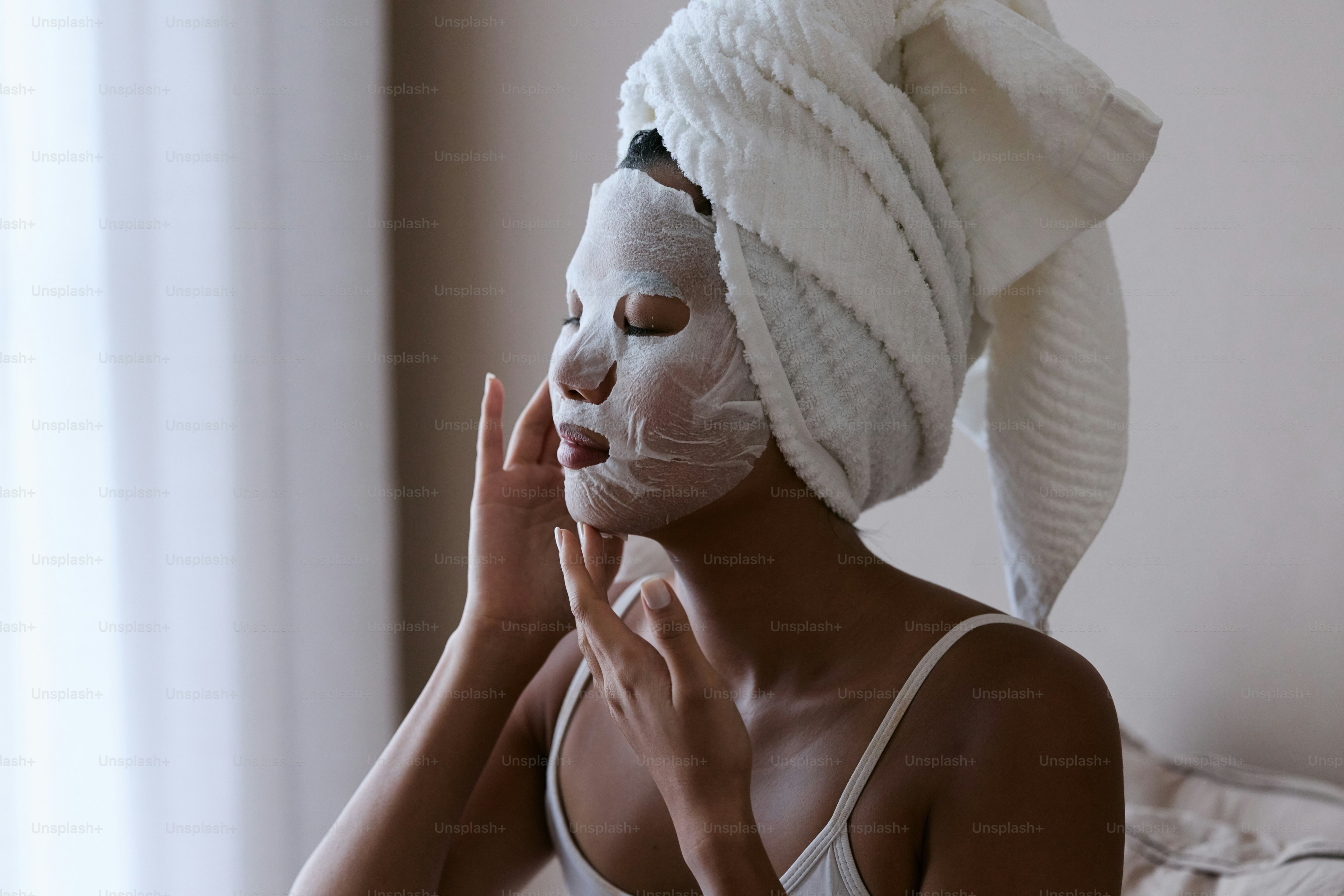 A woman with a towel on her head and a white mask on her face photo ...