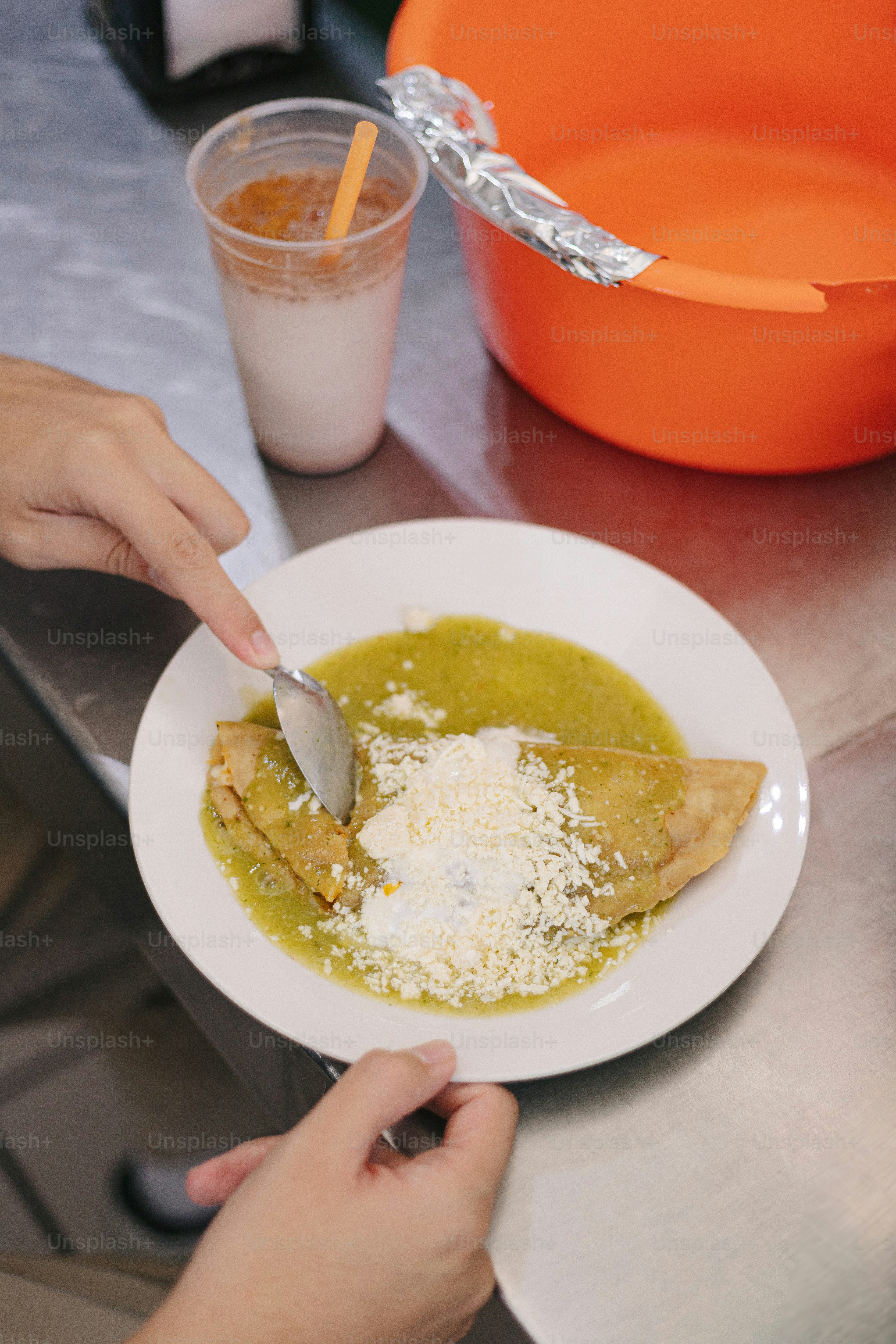 A person eating food from a white plate