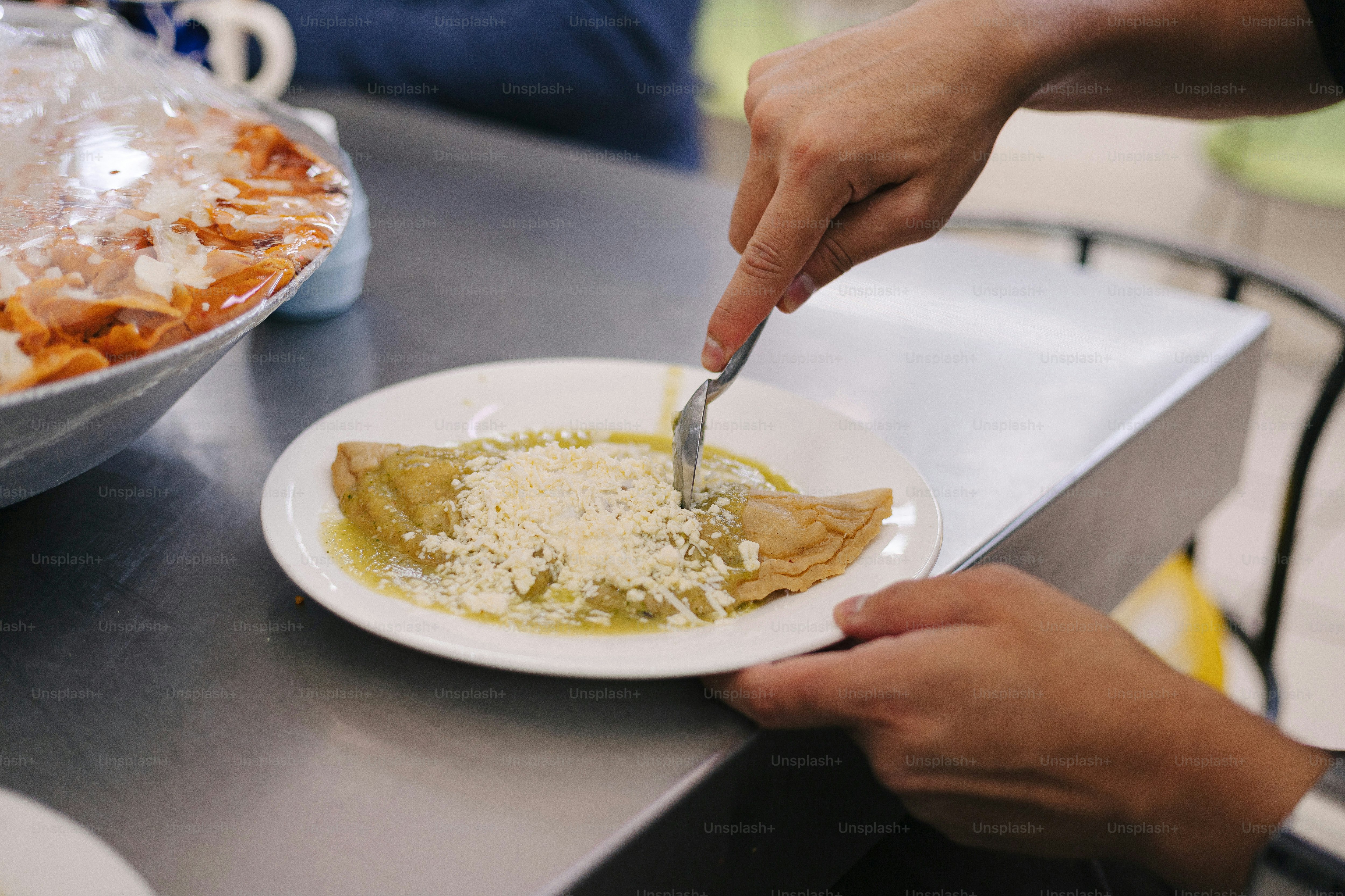 A person cutting a piece of food on a plate