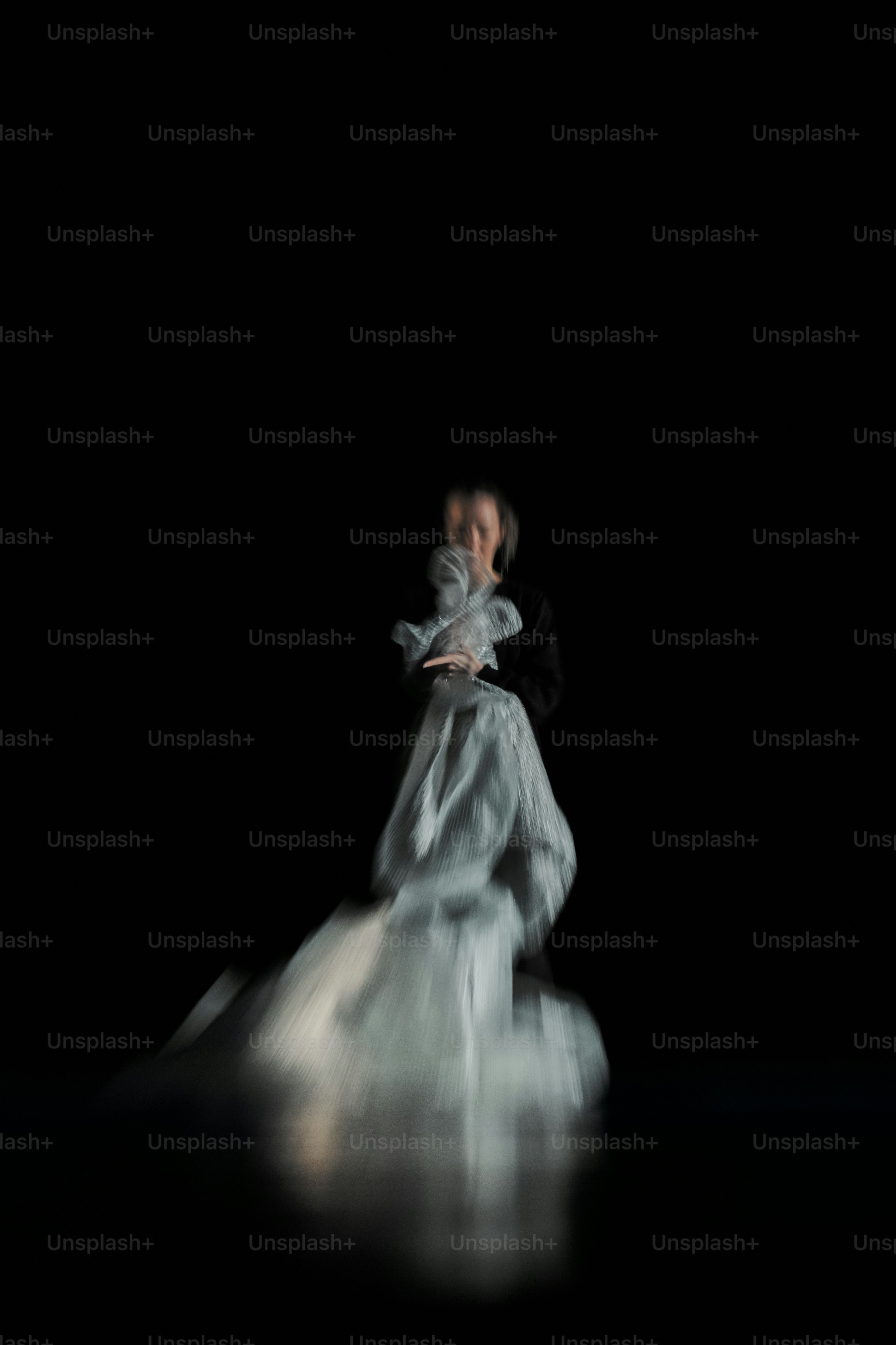 Une femme en robe blanche debout dans l’obscurité