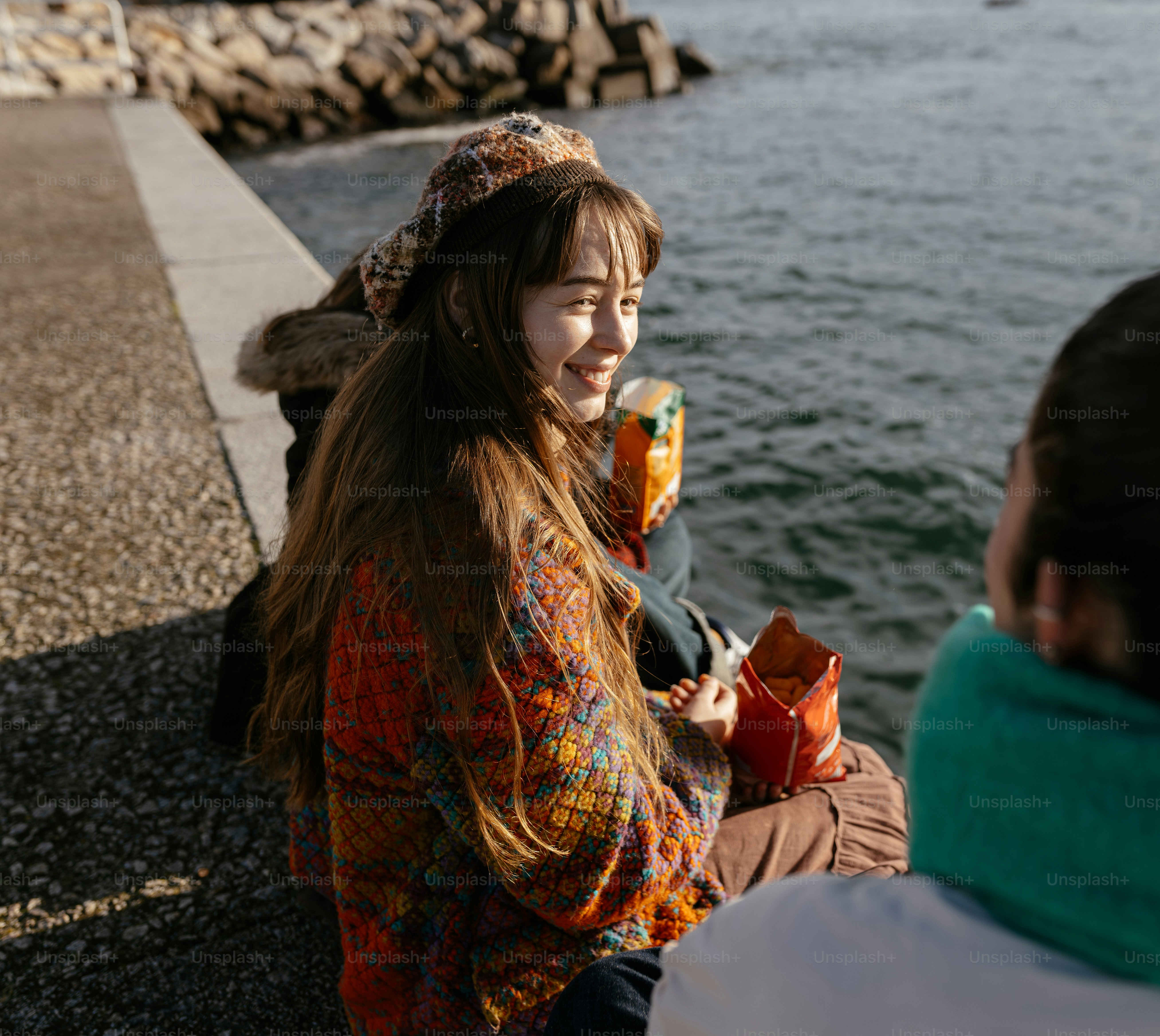 A couple of people sitting next to a body of water