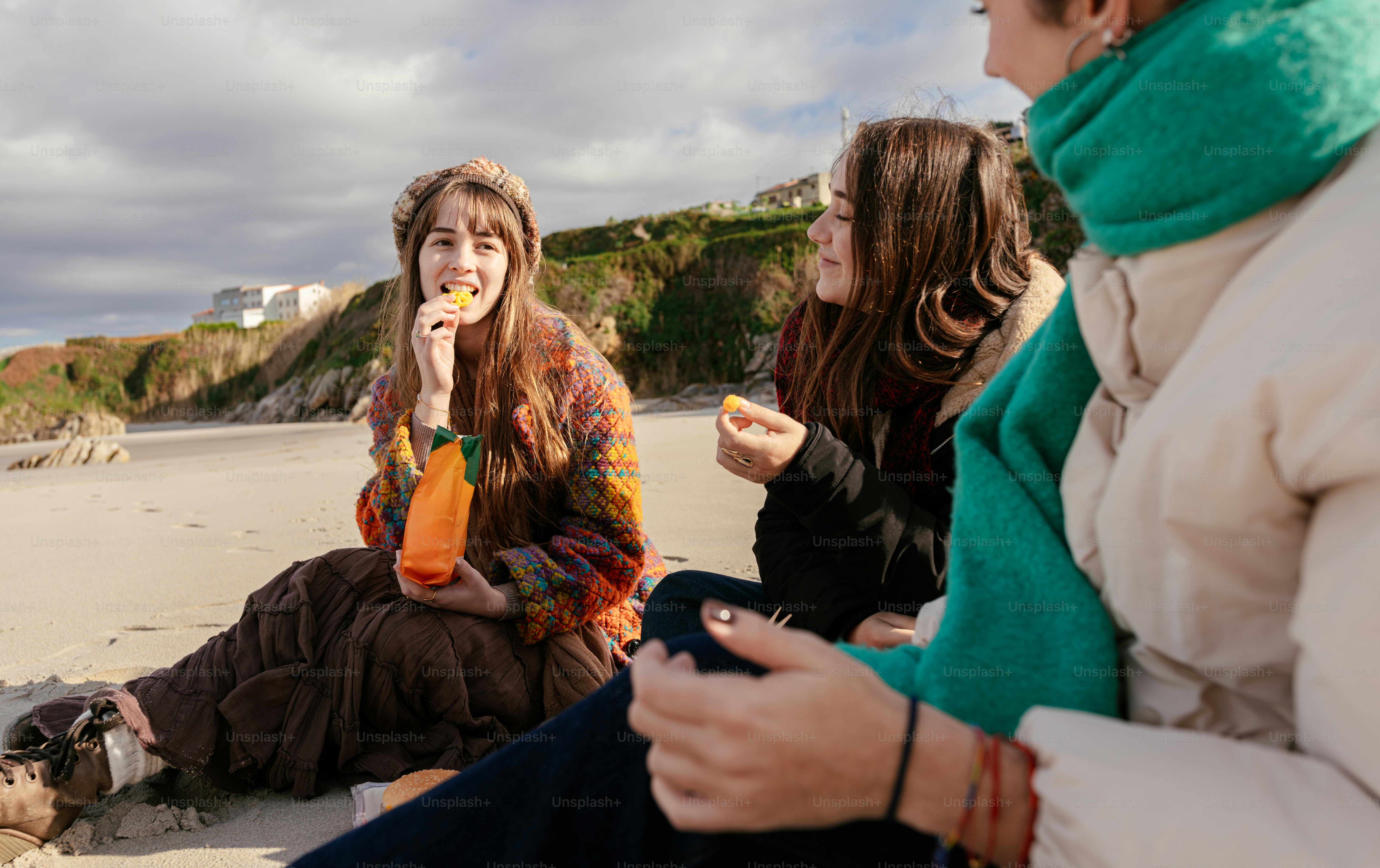 A couple of people sitting next to a body of water photo – Beach Image ...