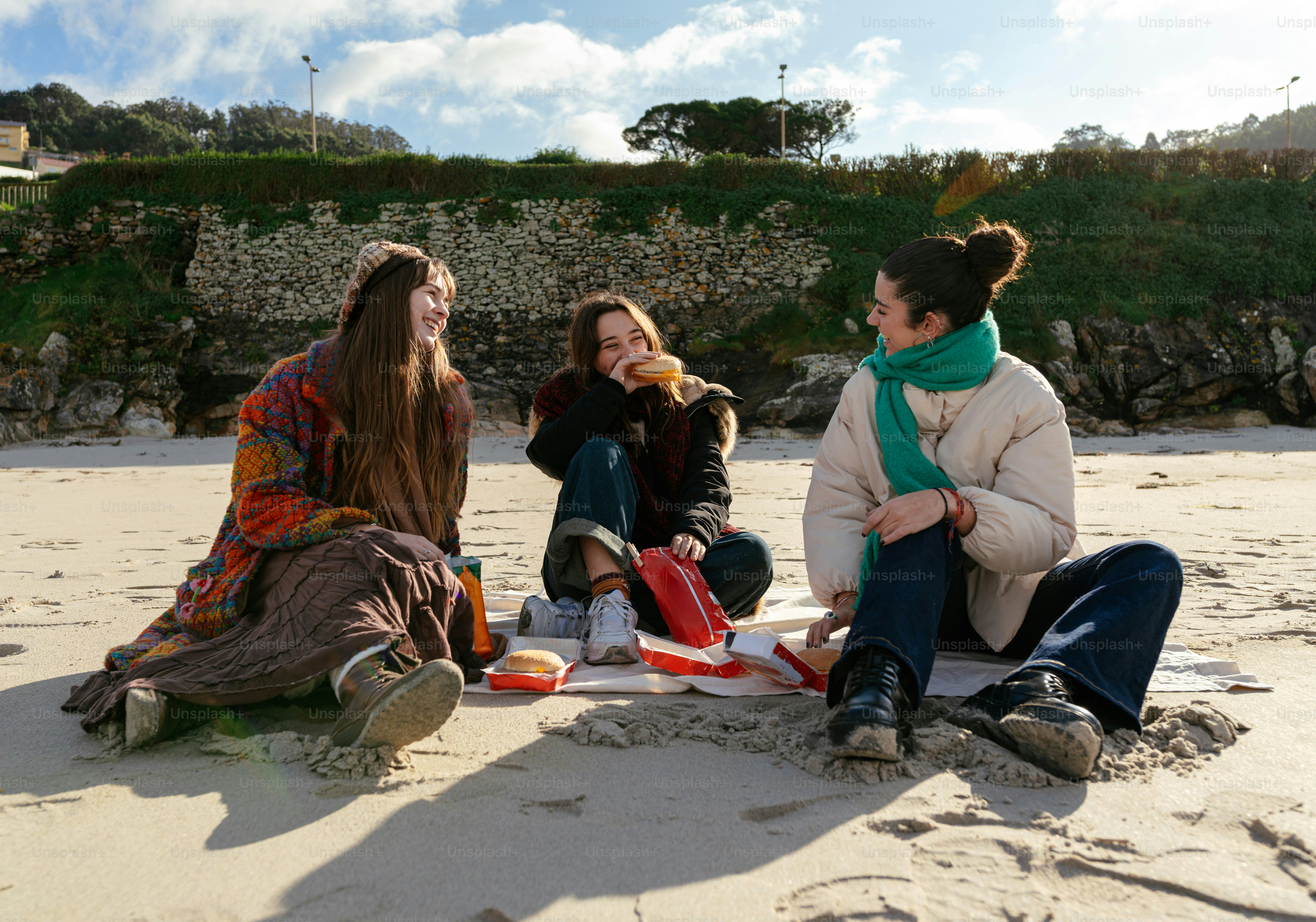 A group of women sitting on top of a sandy beach