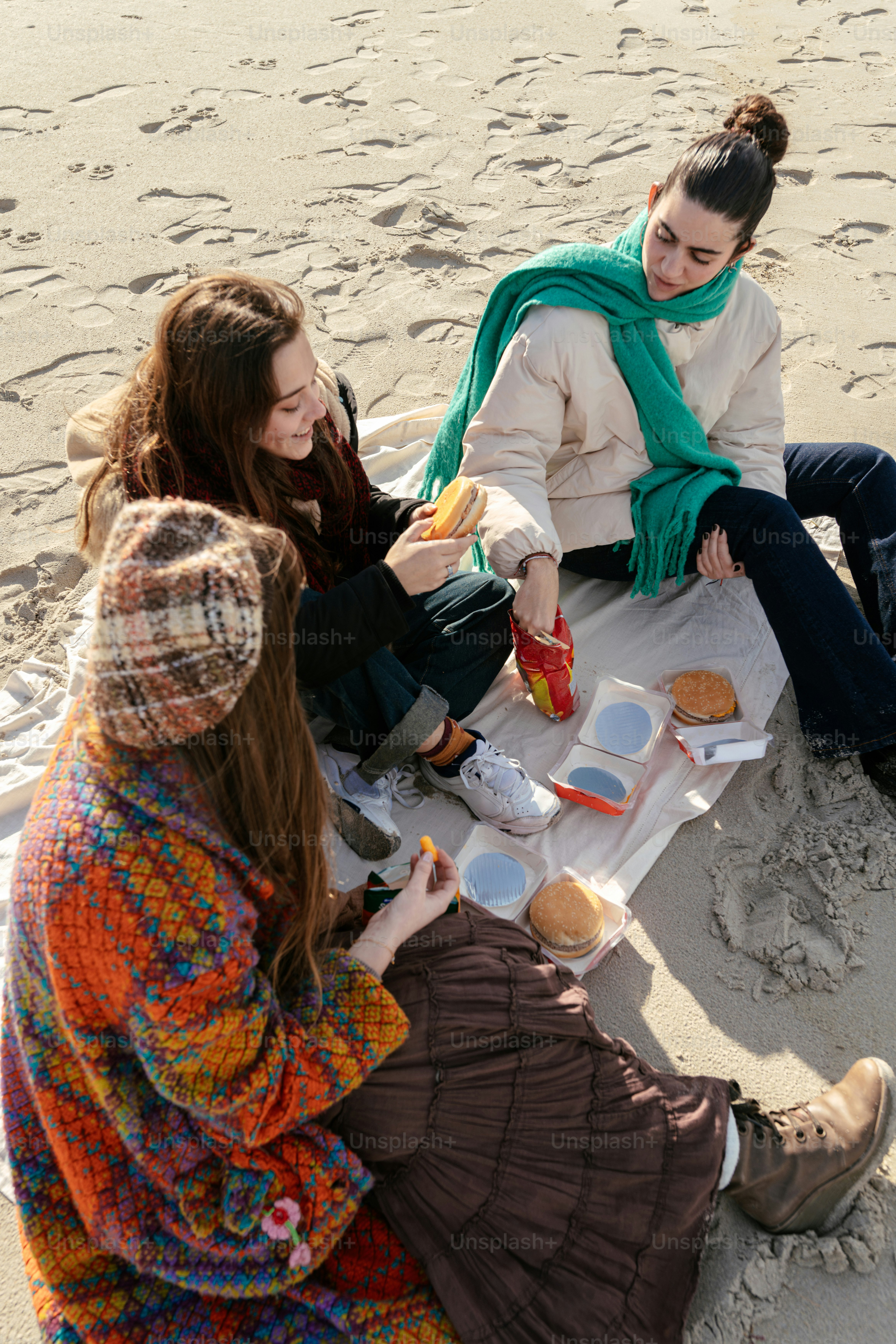 A group of women sitting on top of a sandy beach