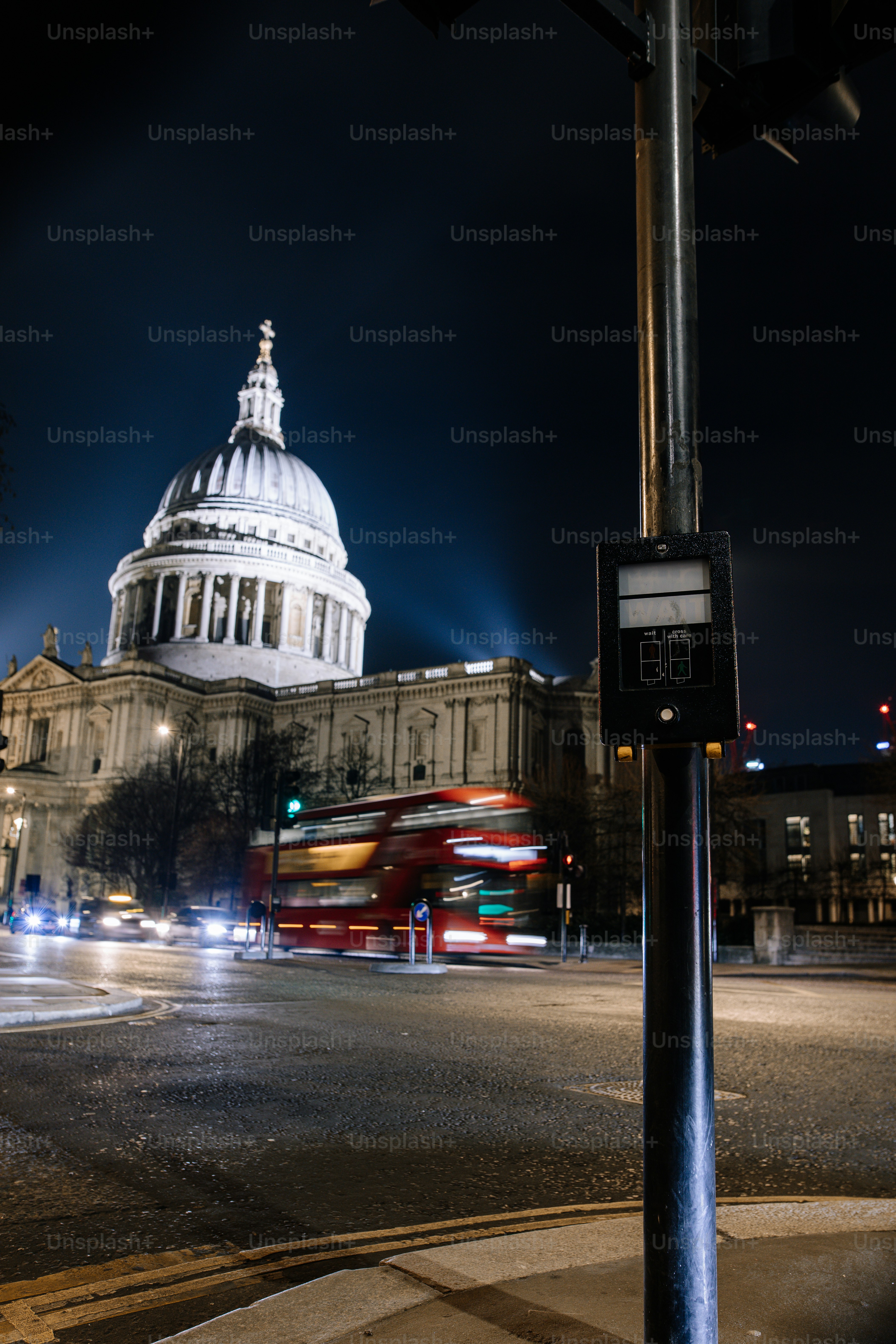 A city street at night with a large building in the background
