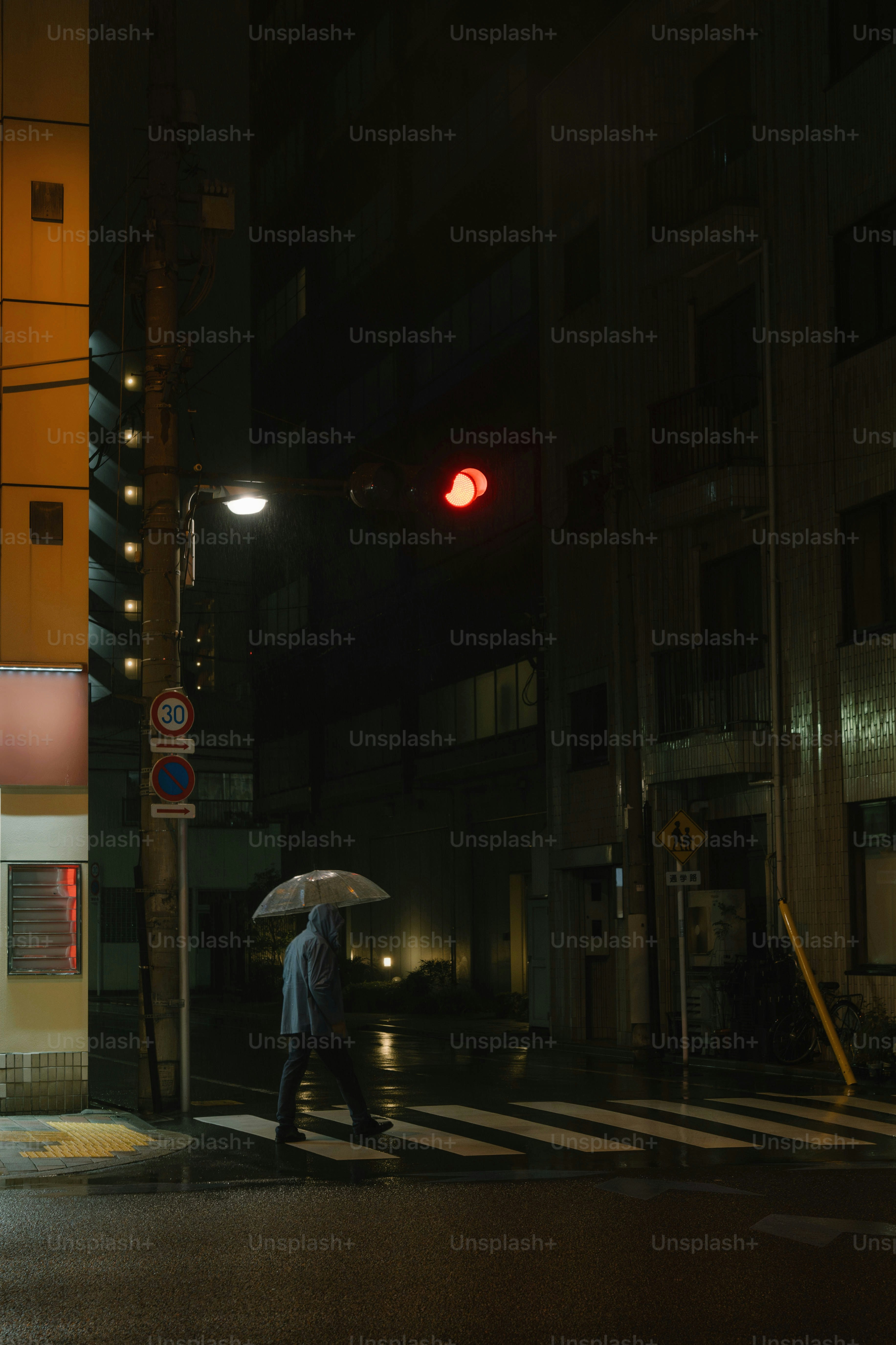 A man walking across a street holding an umbrella