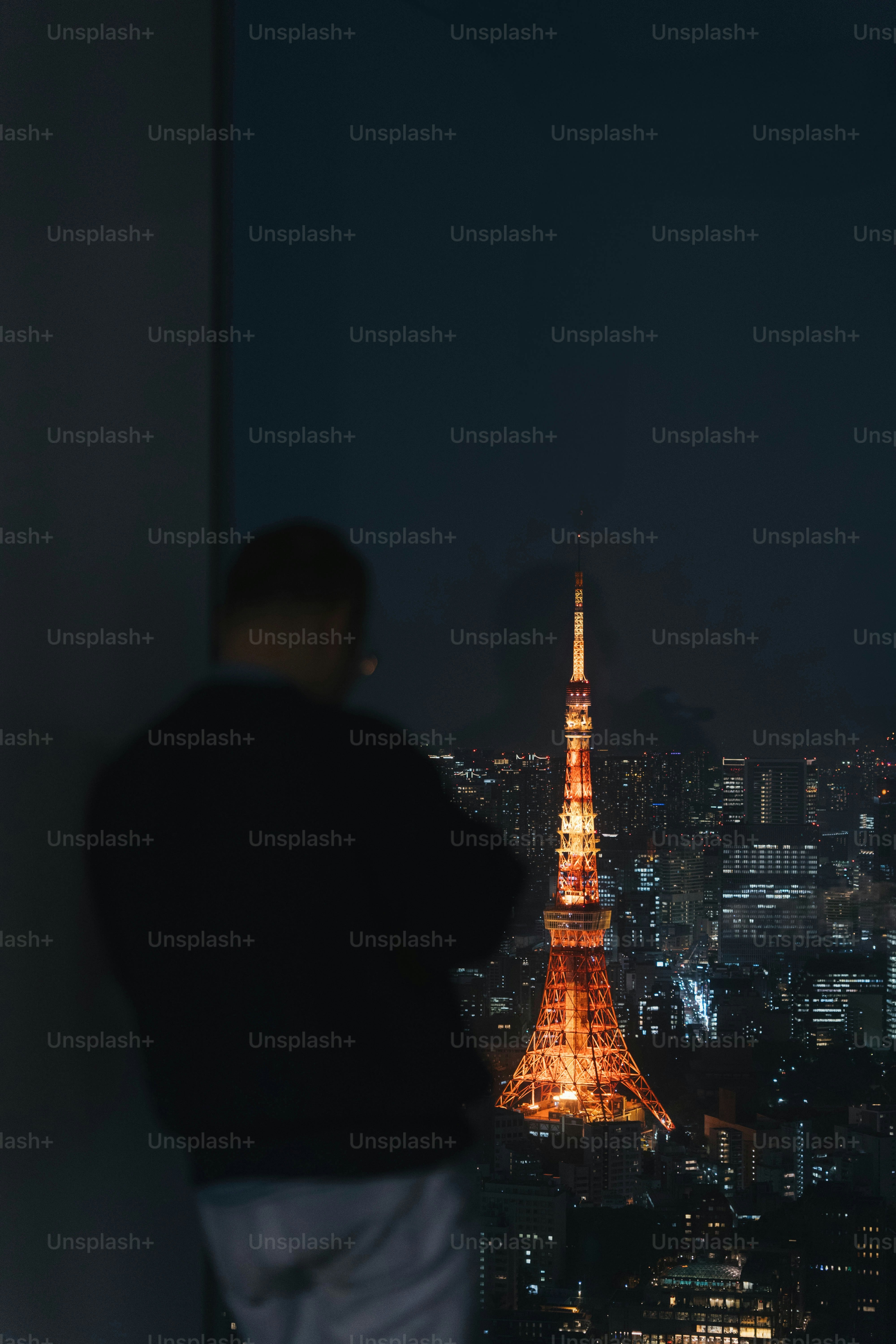 Un hombre de pie frente a una ventana mirando la torre Eiffel