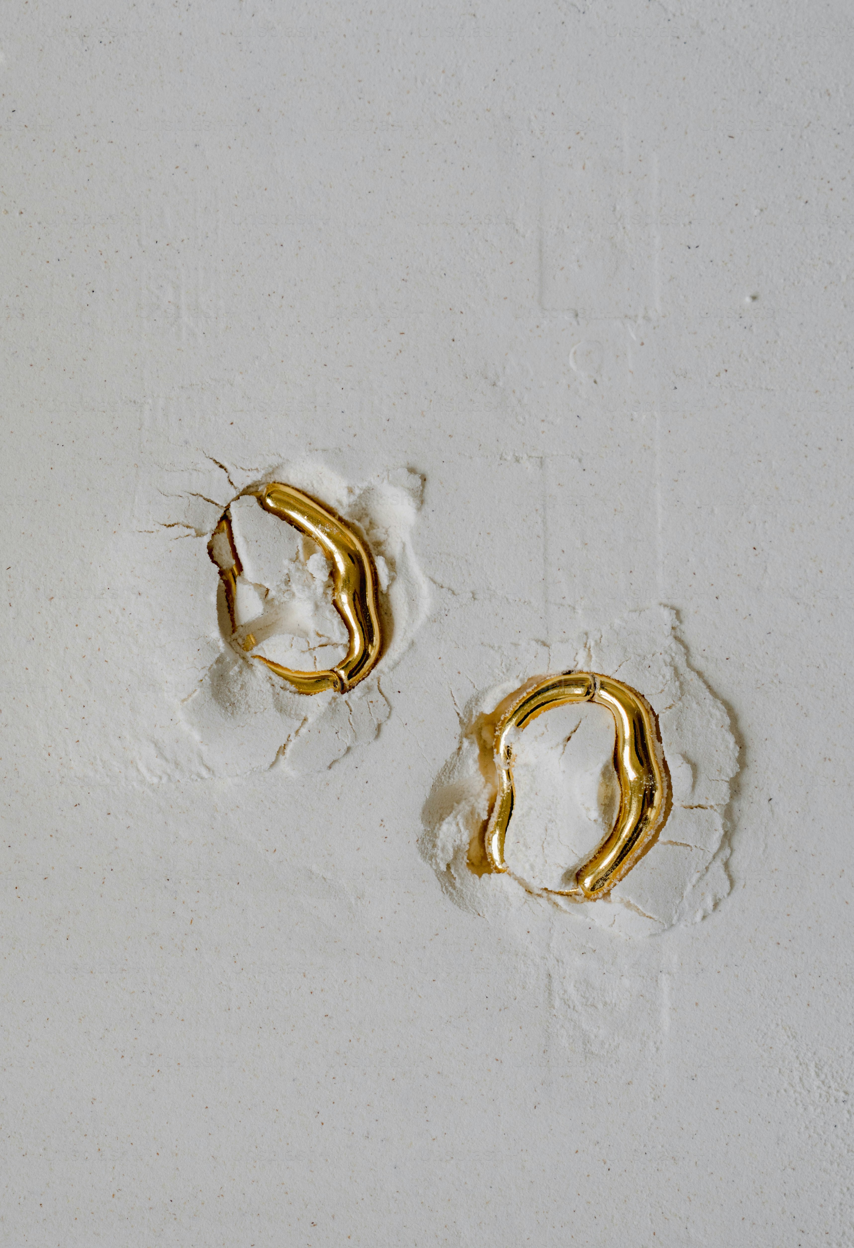 A couple of gold rings sitting on top of a white wall
