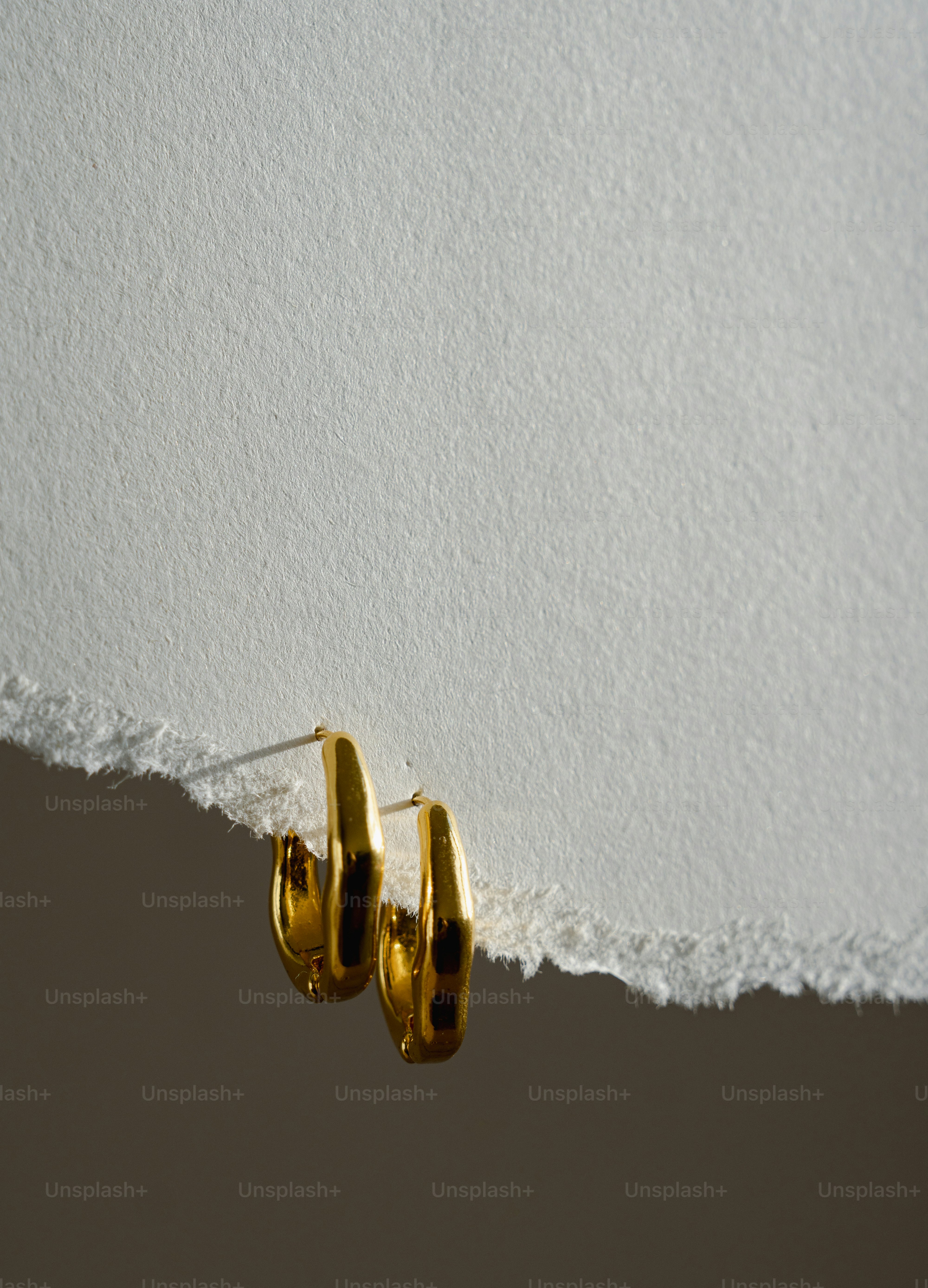 A pair of gold hoop earrings hanging from a wall