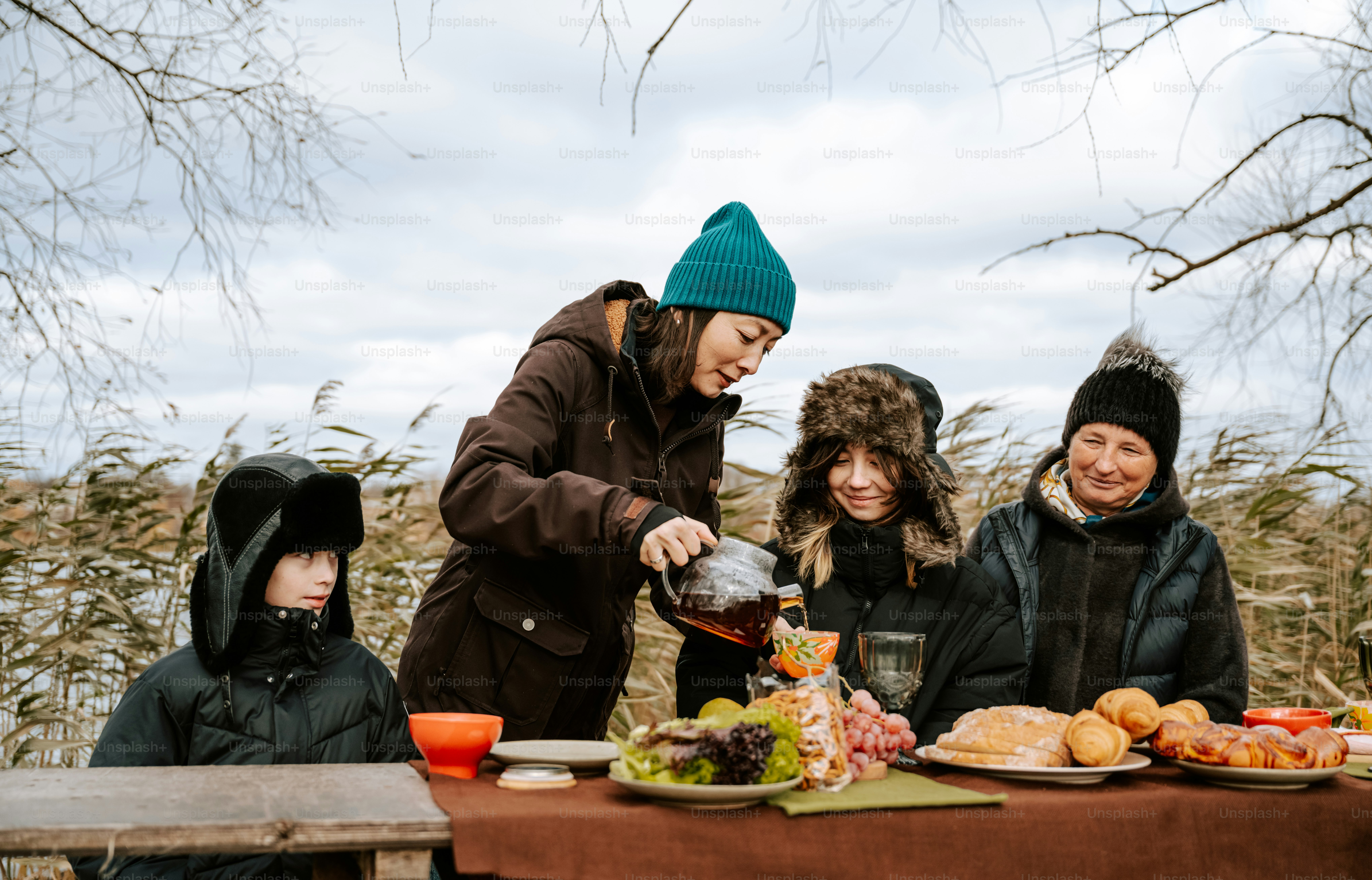 A group of people standing around a table with plates of food photo ...