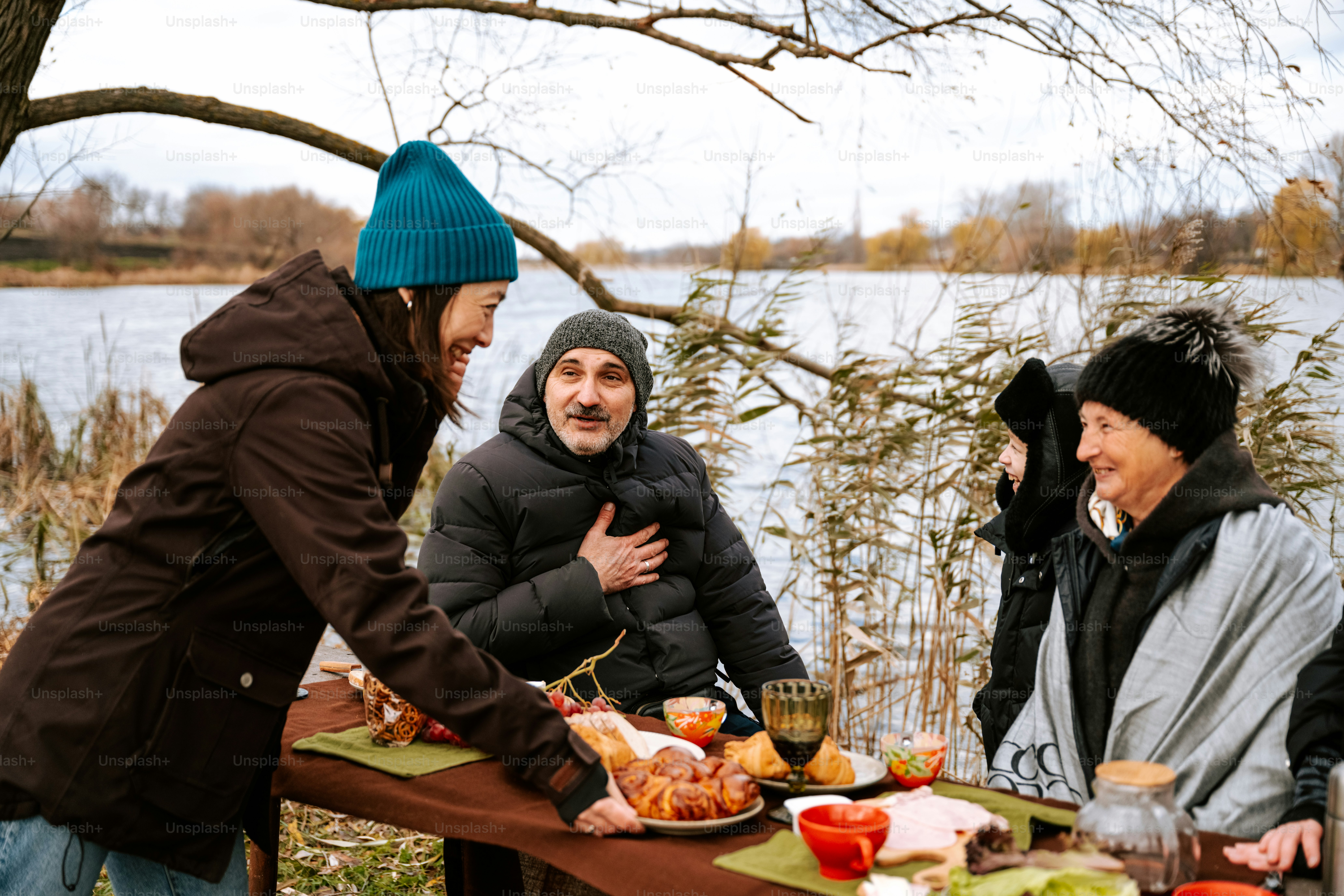 A group of people sitting around a table with food on it photo – Autumn ...