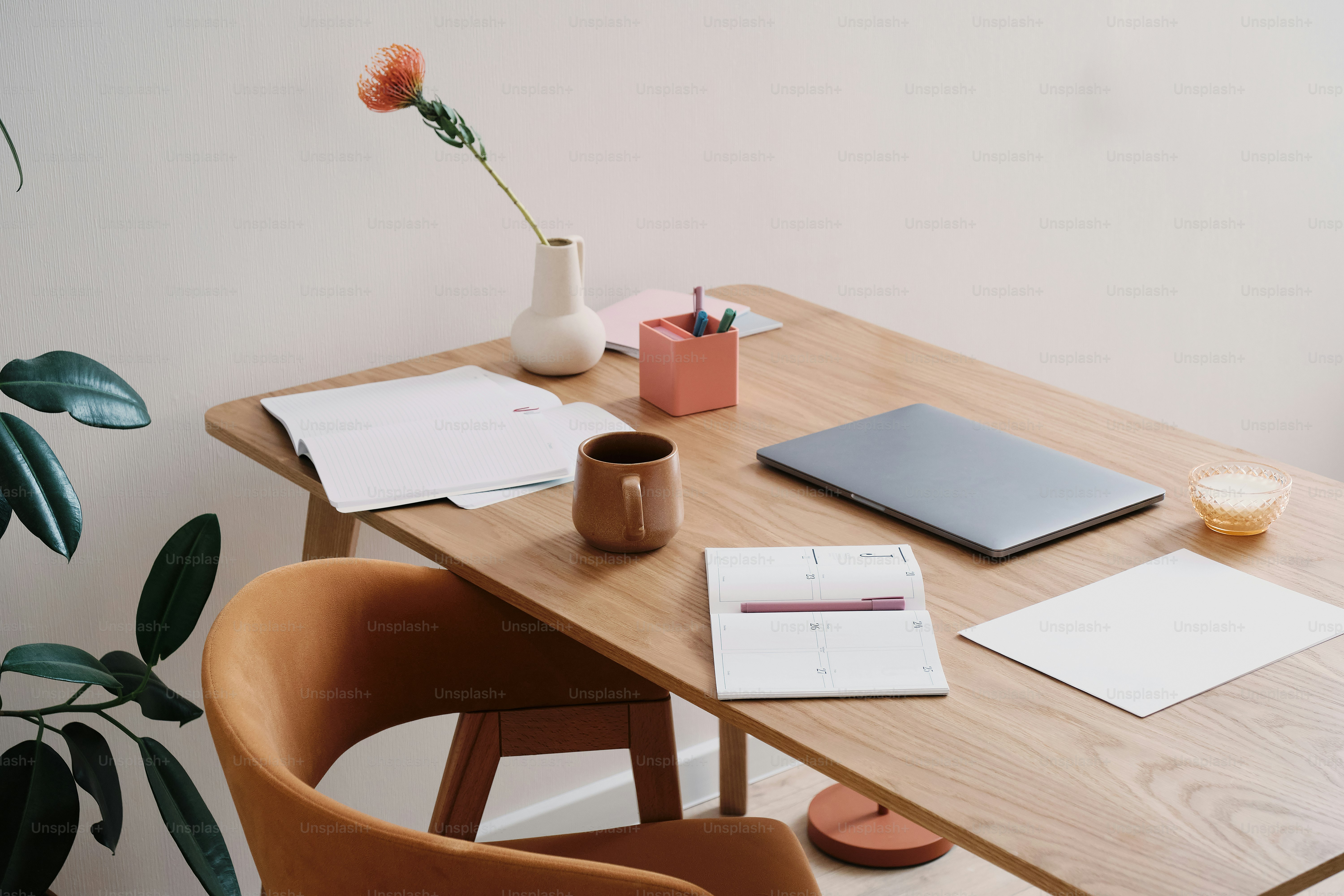 Uma mesa com um laptop, caderno e flor