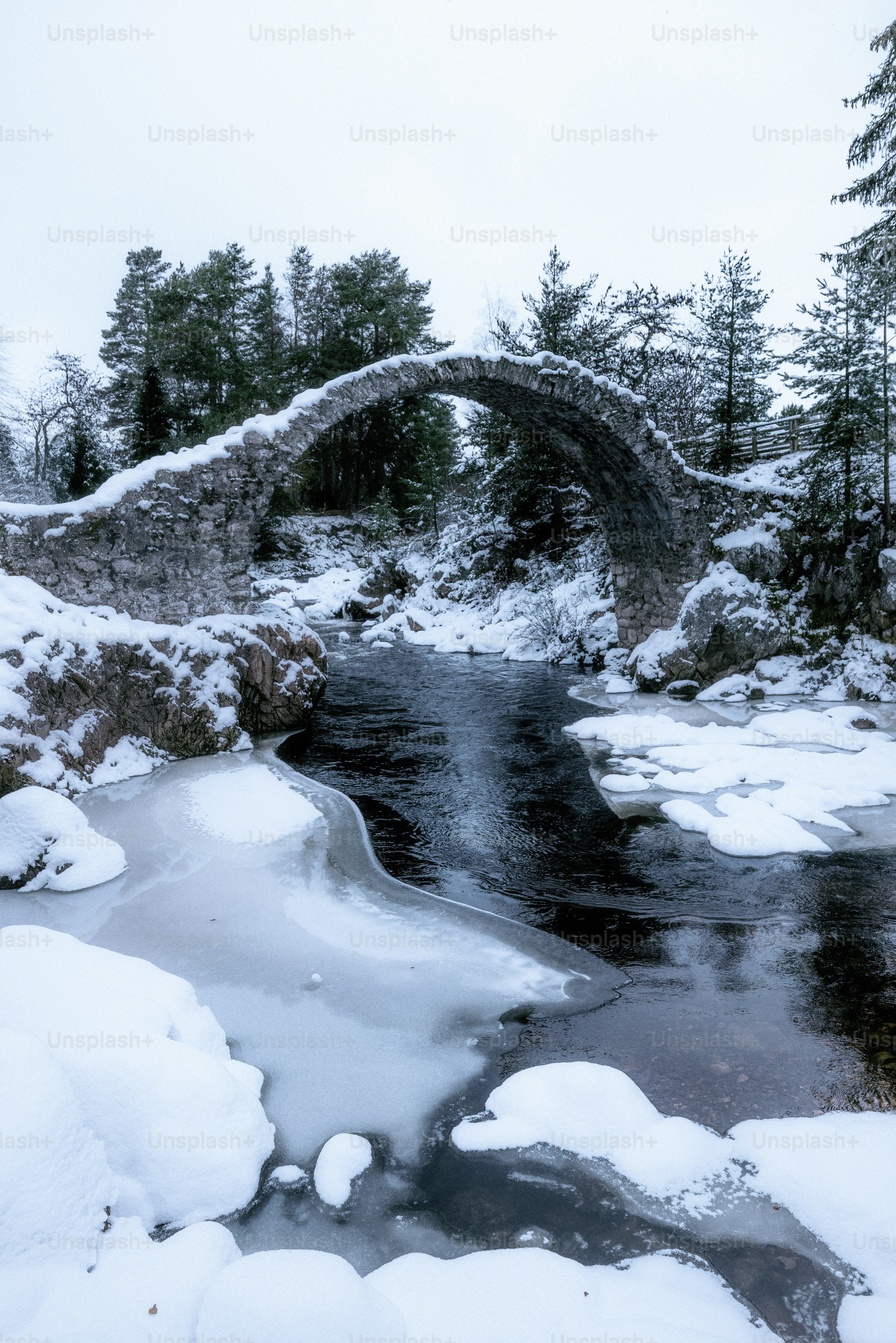 A snow covered bridge over a small stream