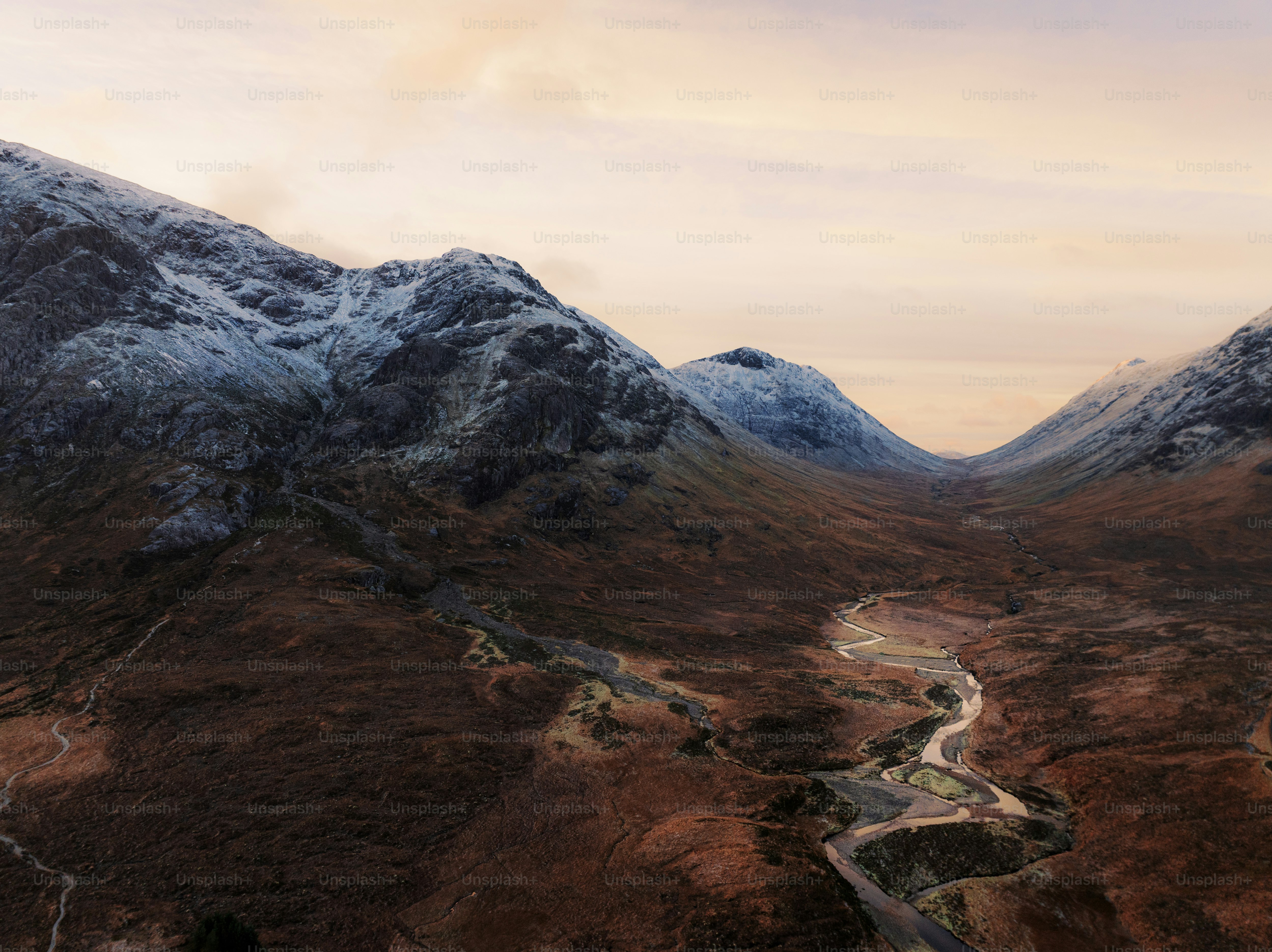 A mountain range with a winding road in the foreground