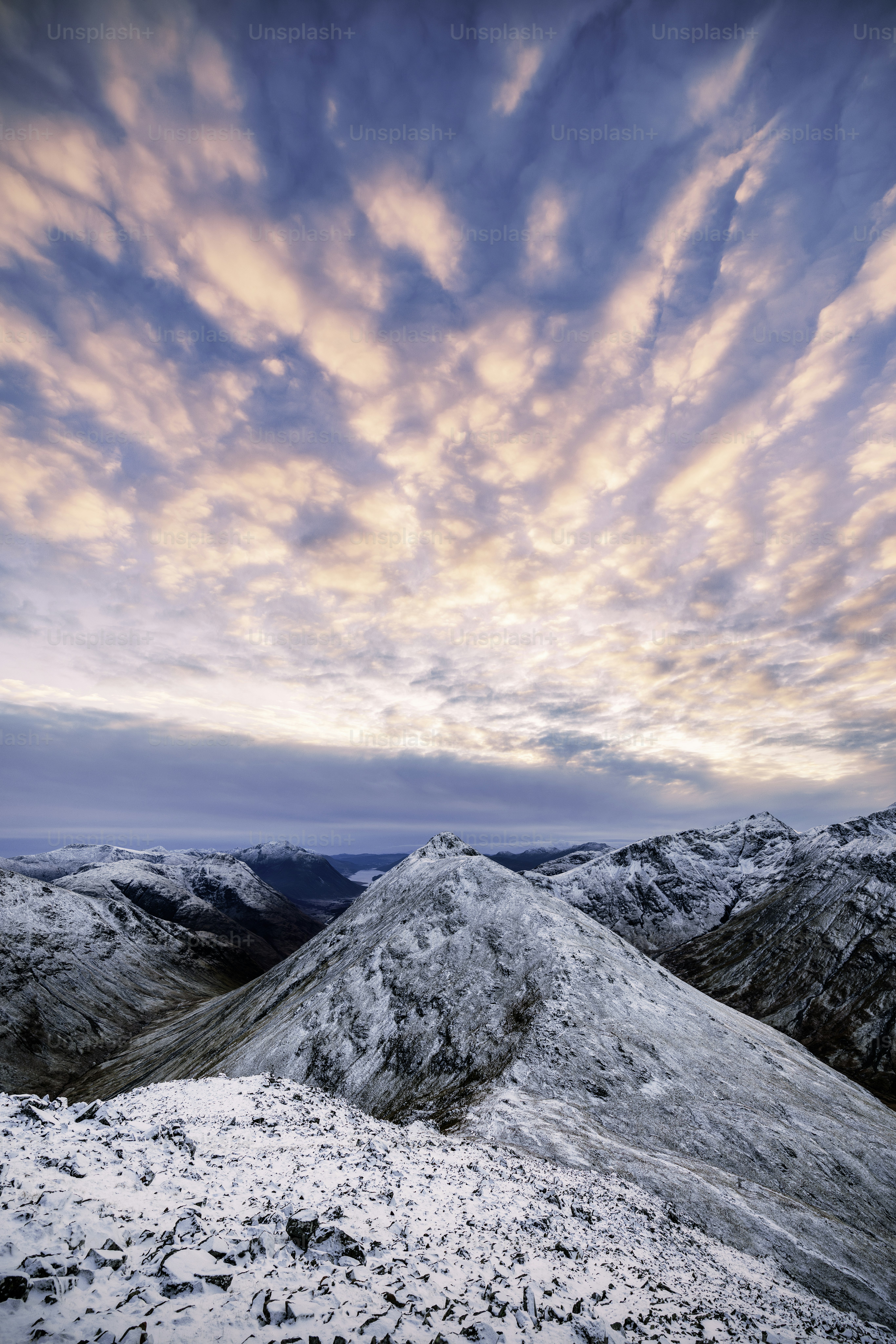 A mountain covered in snow under a cloudy sky