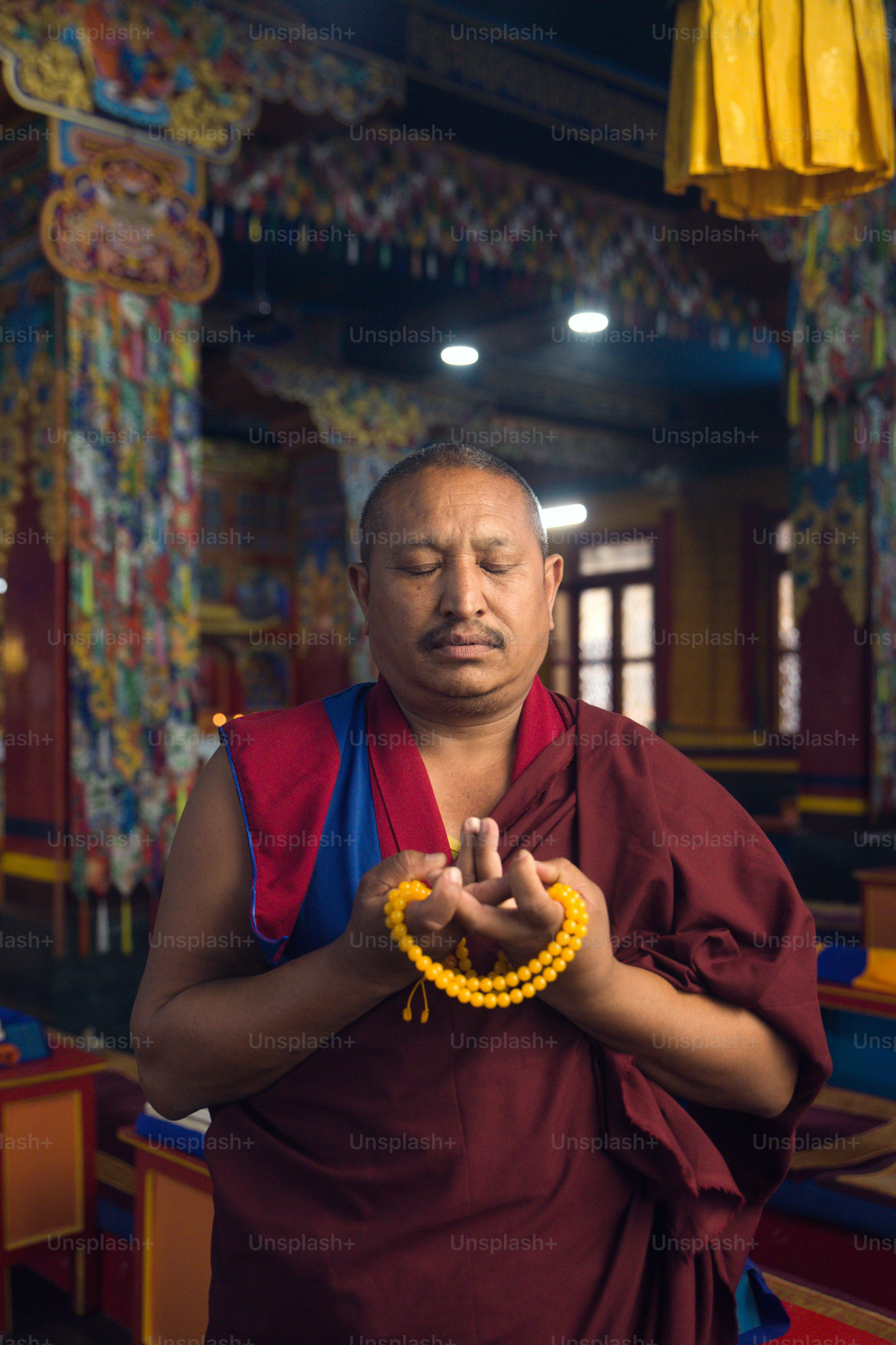 A man standing in a room holding a beaded bracelet photo – Meditation Image  on Unsplash, image size:3000x4500
