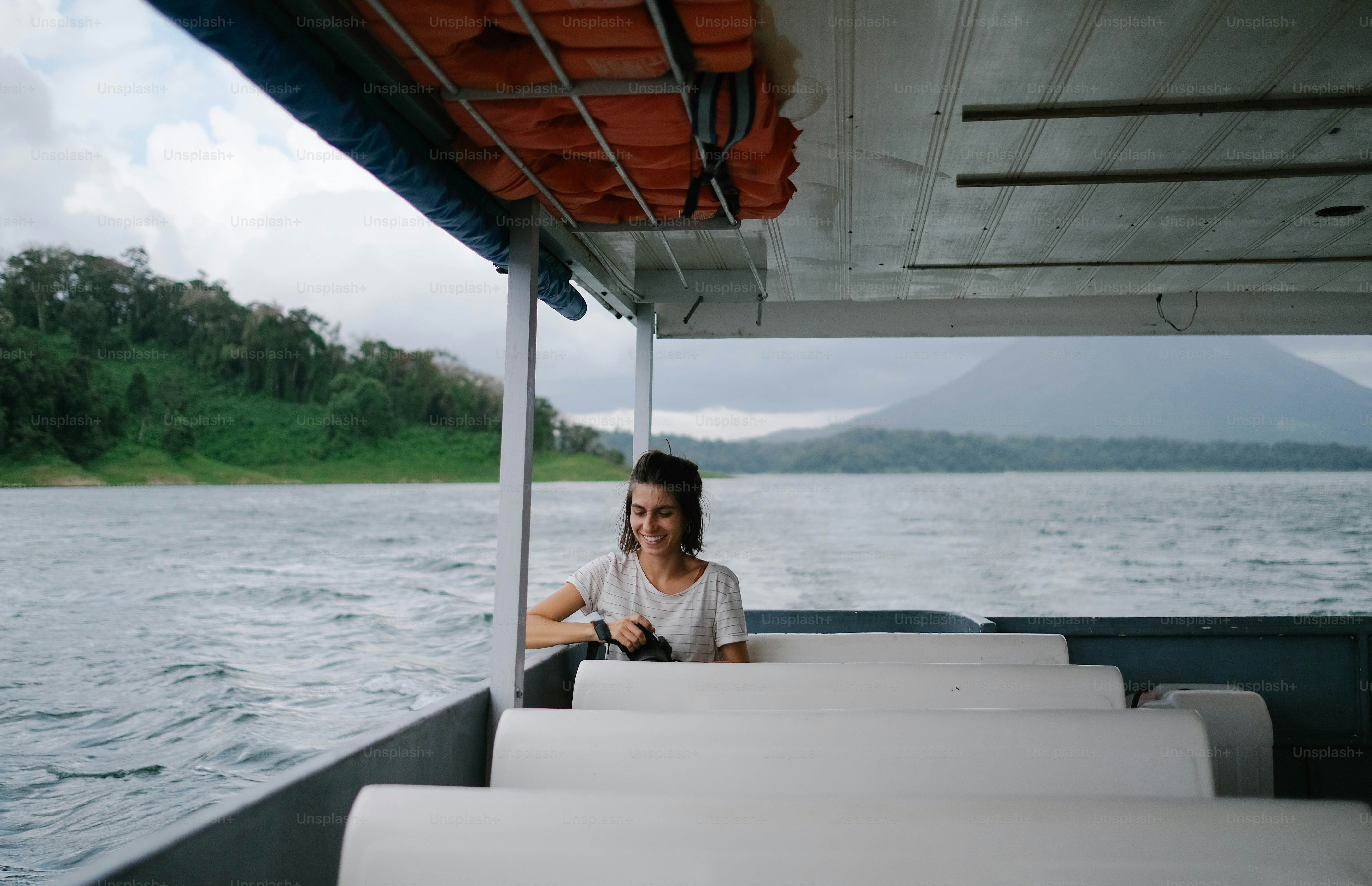 A woman sitting on a boat in the water photo – Travelling alone Image ...