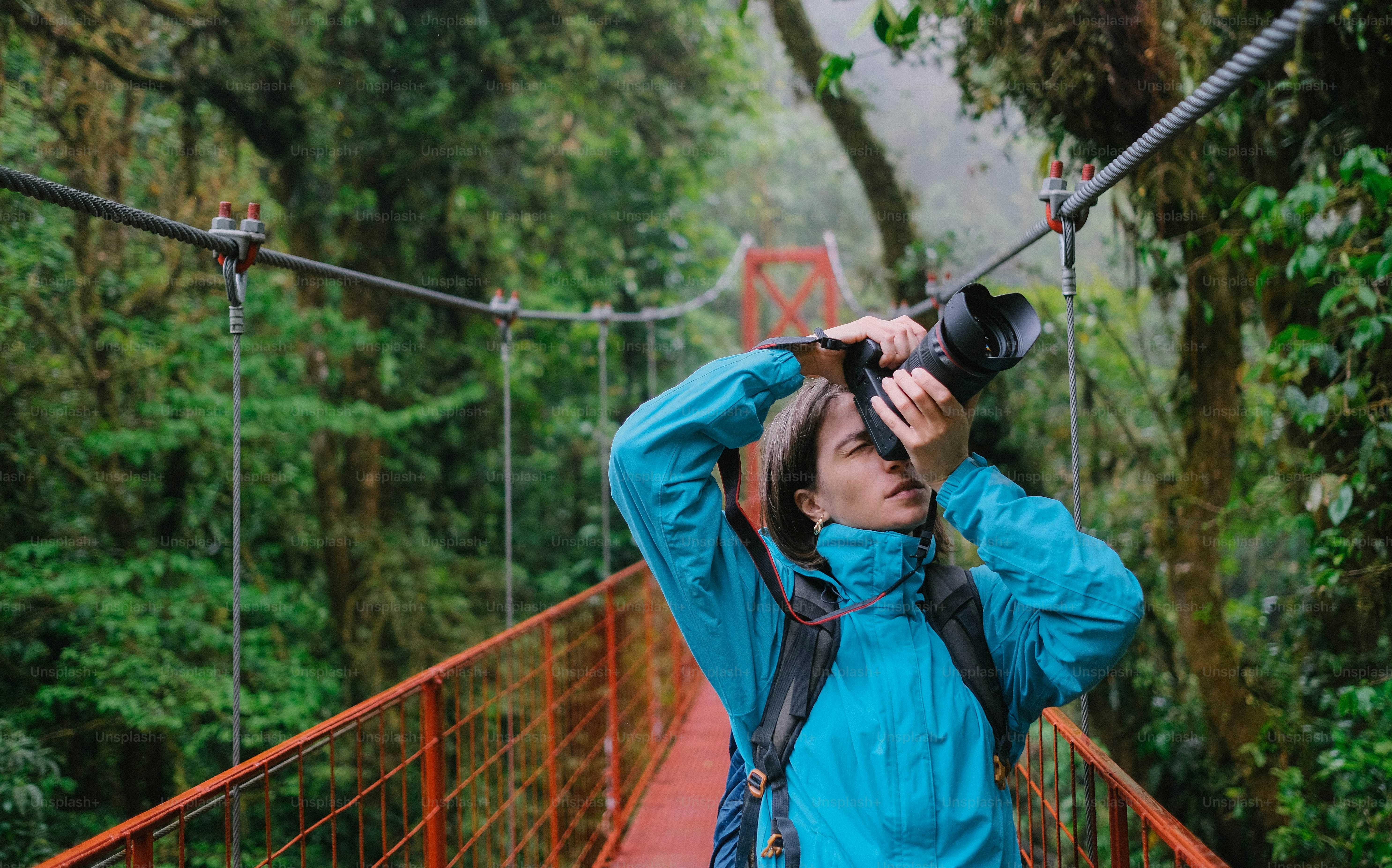 A woman standing on a suspension bridge with a camera