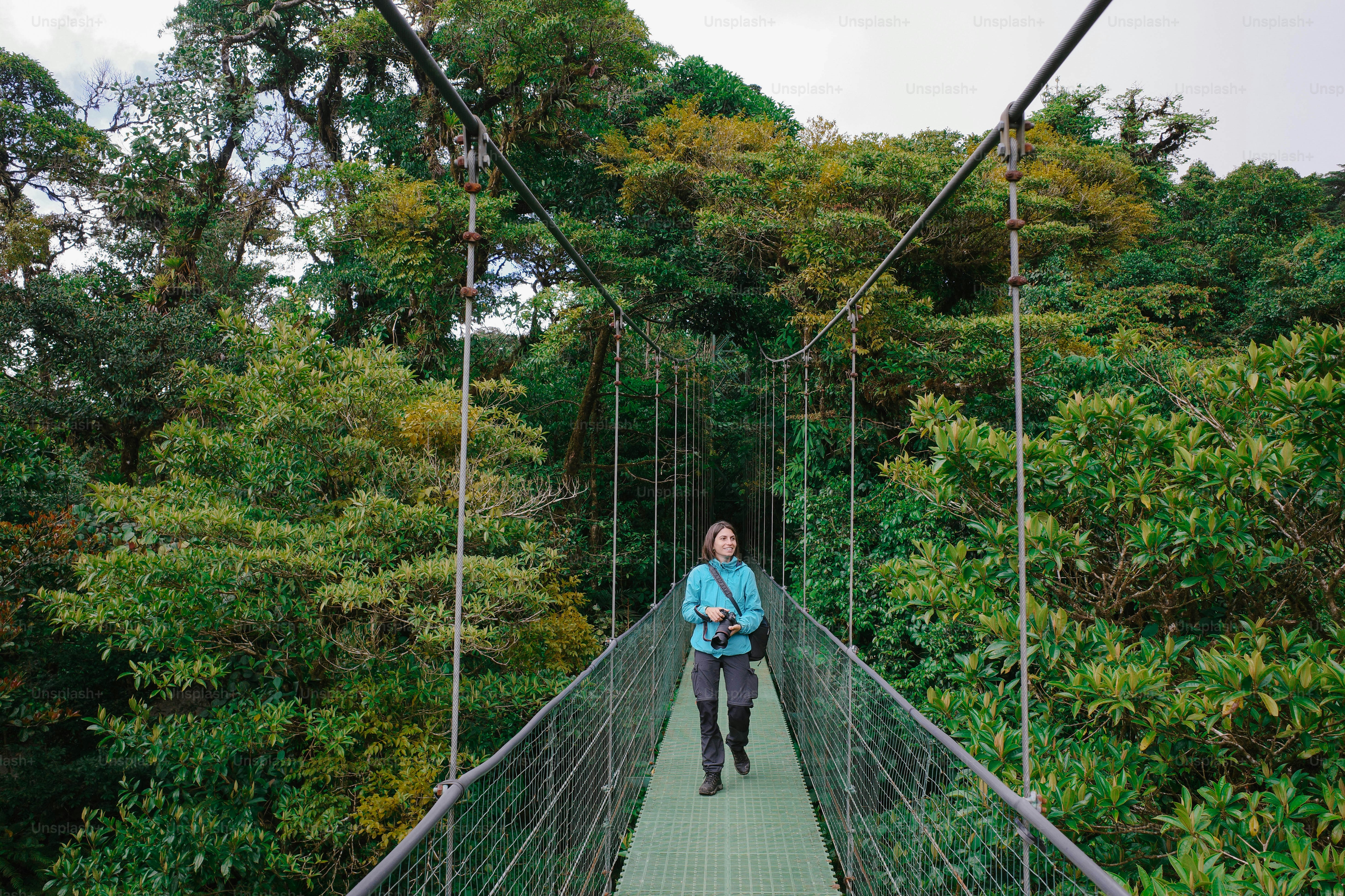 A woman walking across a suspension bridge in a forest