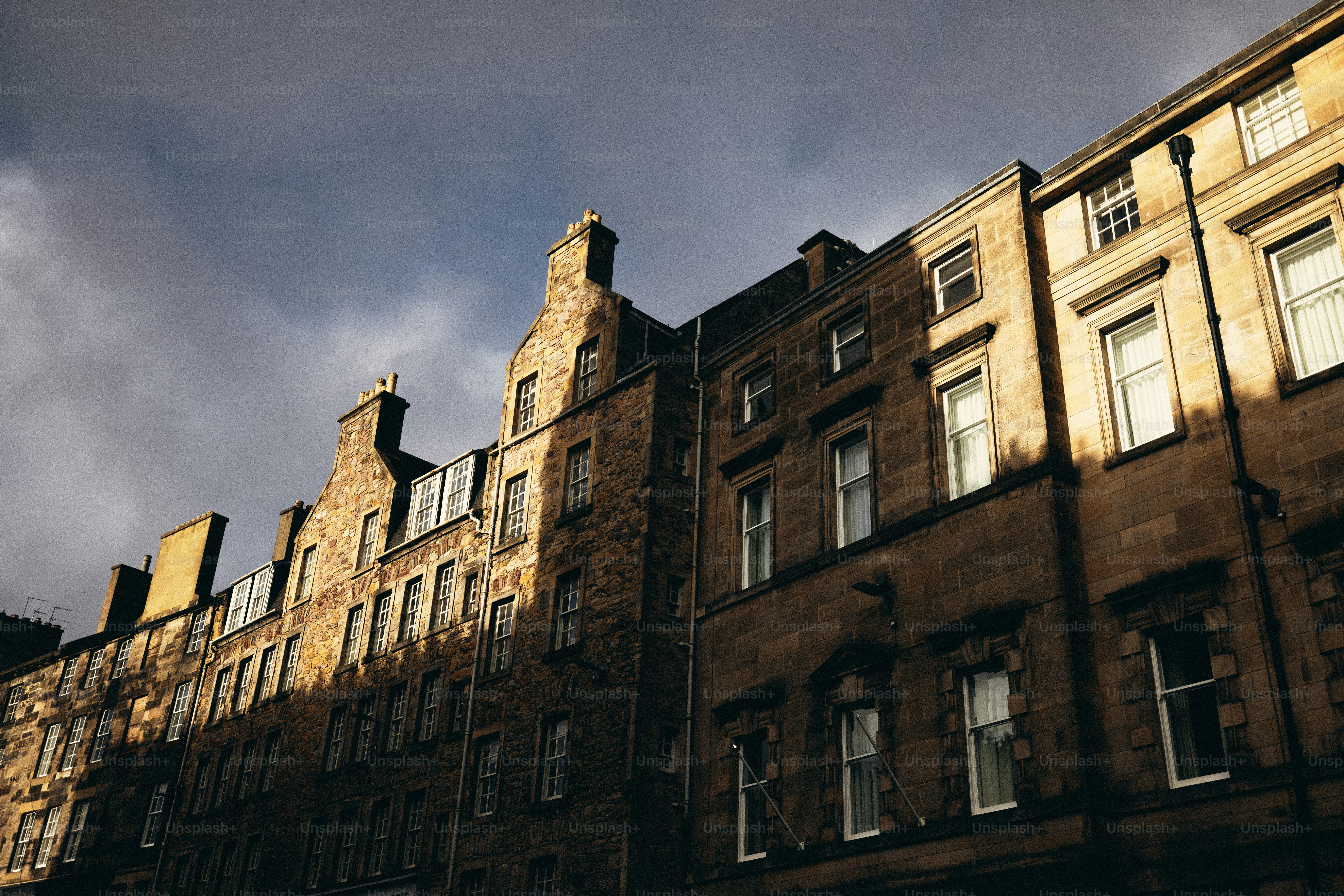 A row of brown buildings with a cloudy sky in the background