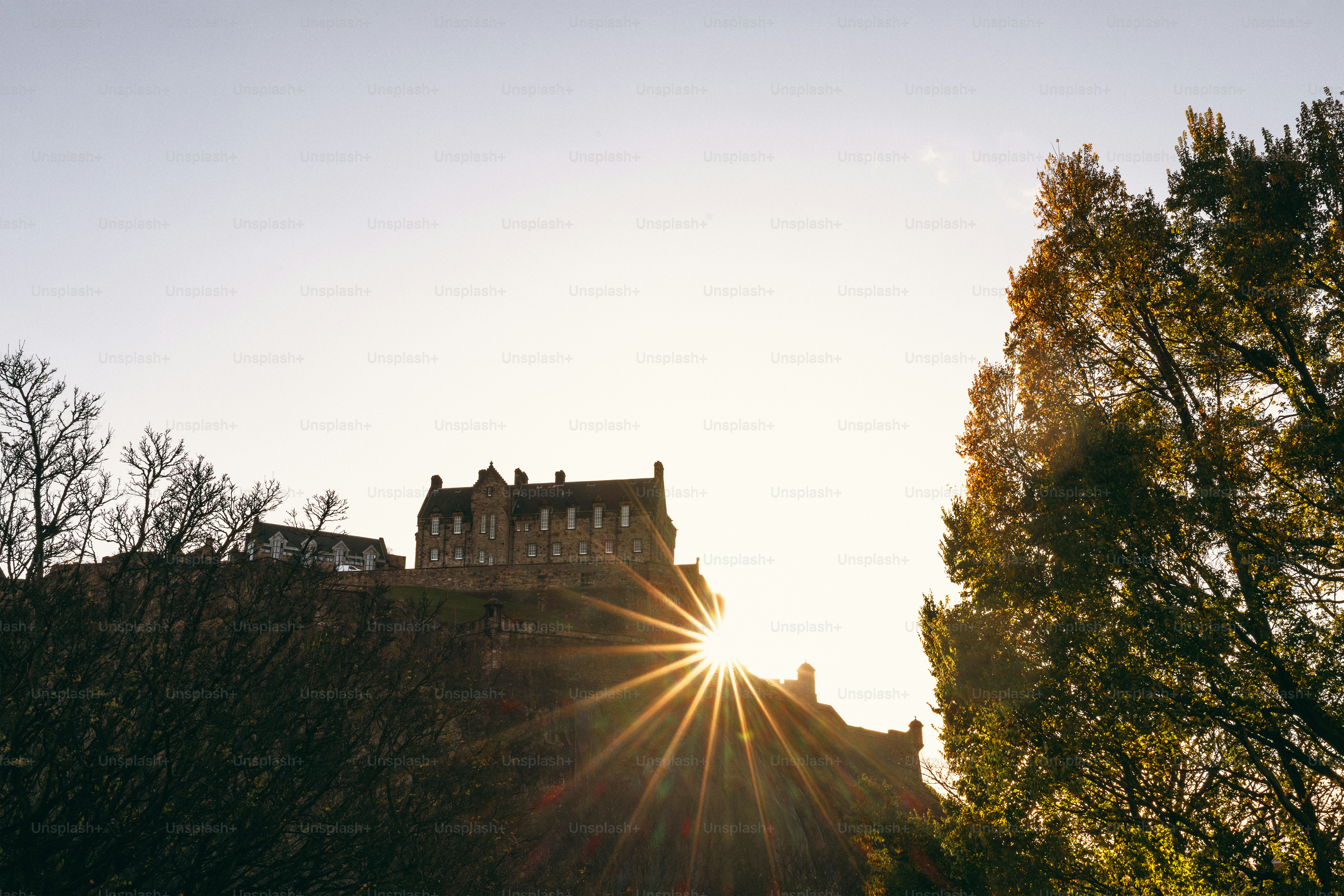 The sun is shining over a castle on a hill