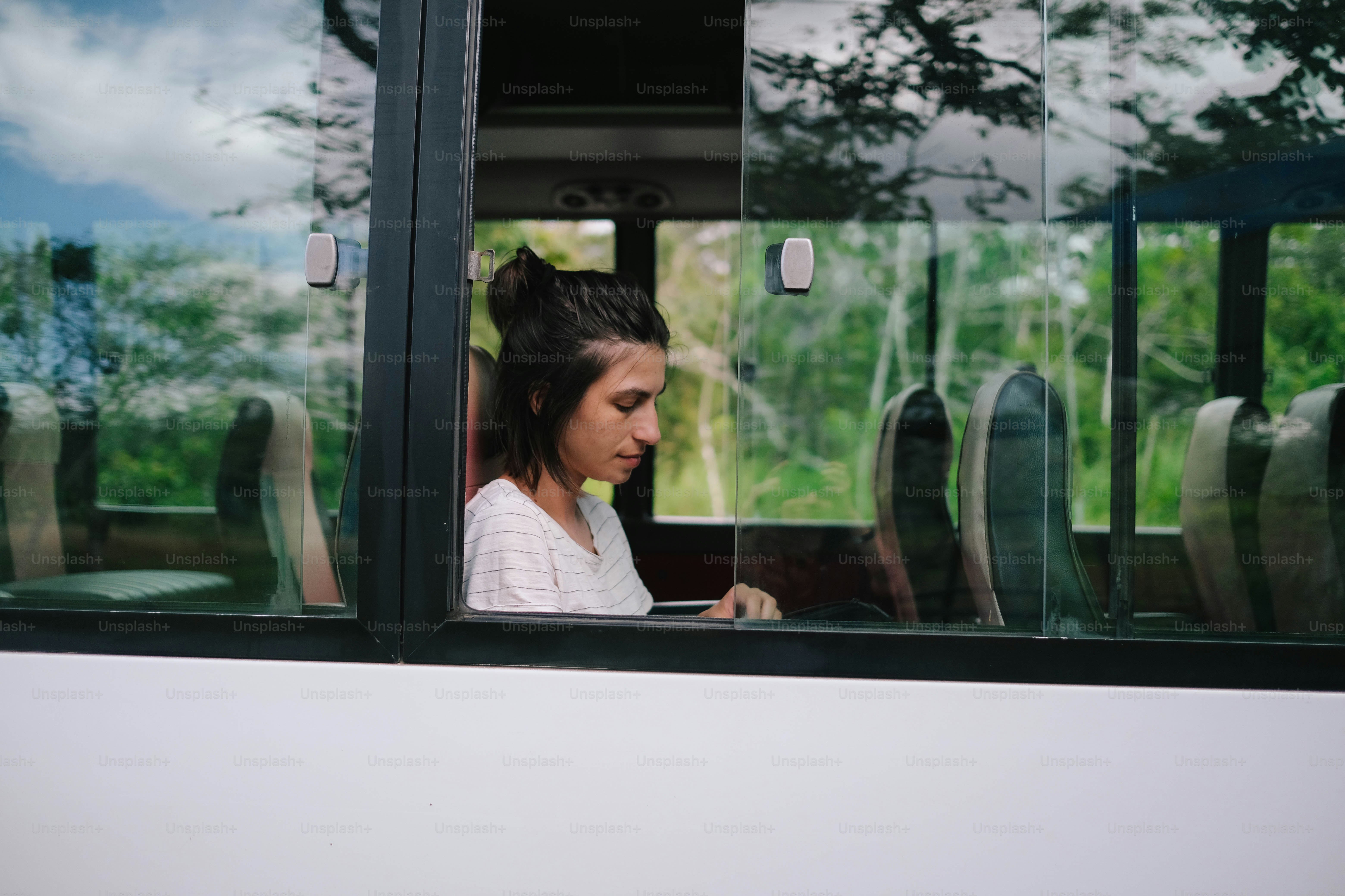 A woman sitting on a bus looking out the window photo – Woman Image on ...
