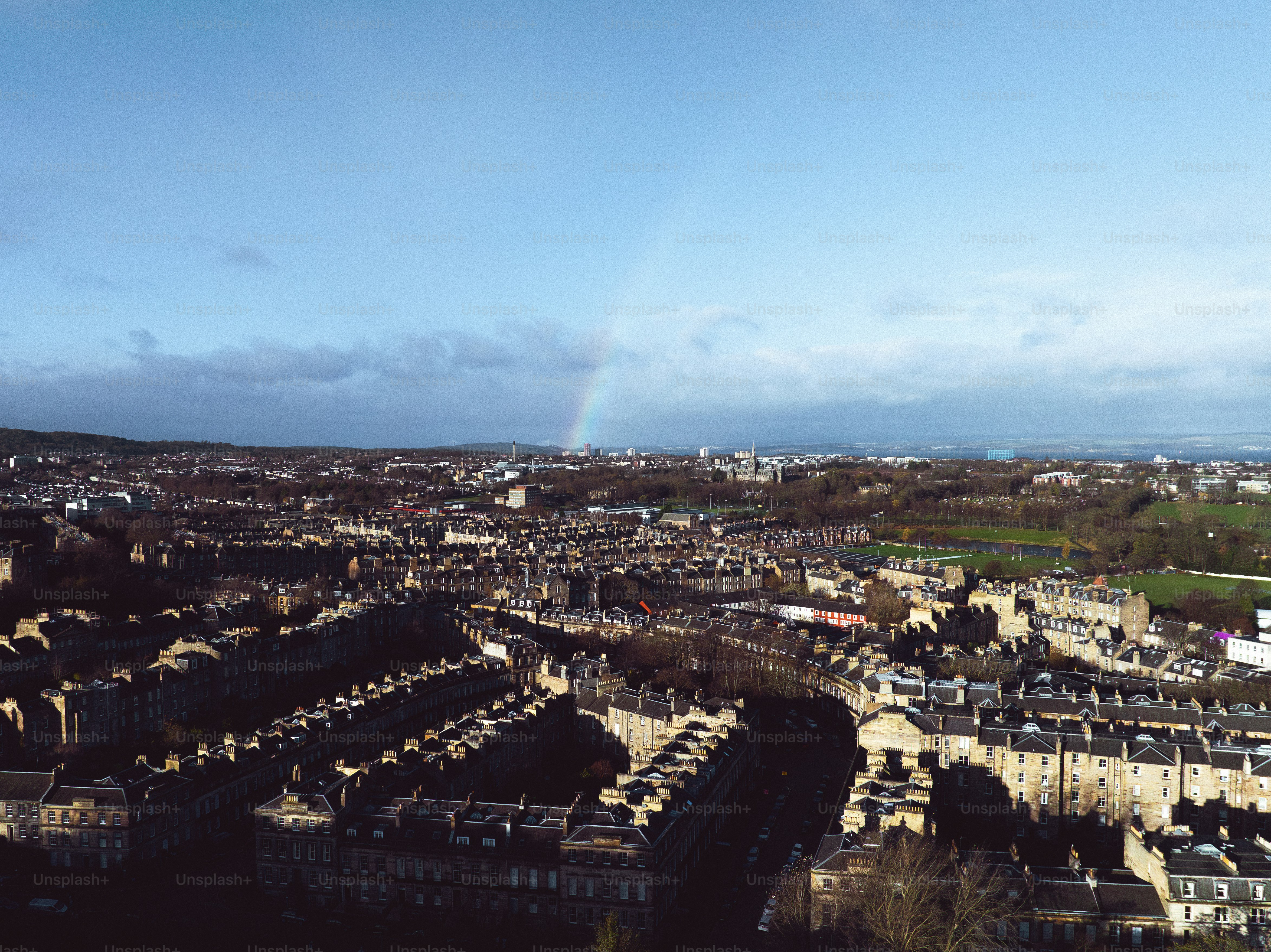 An aerial view of a city with a rainbow in the sky