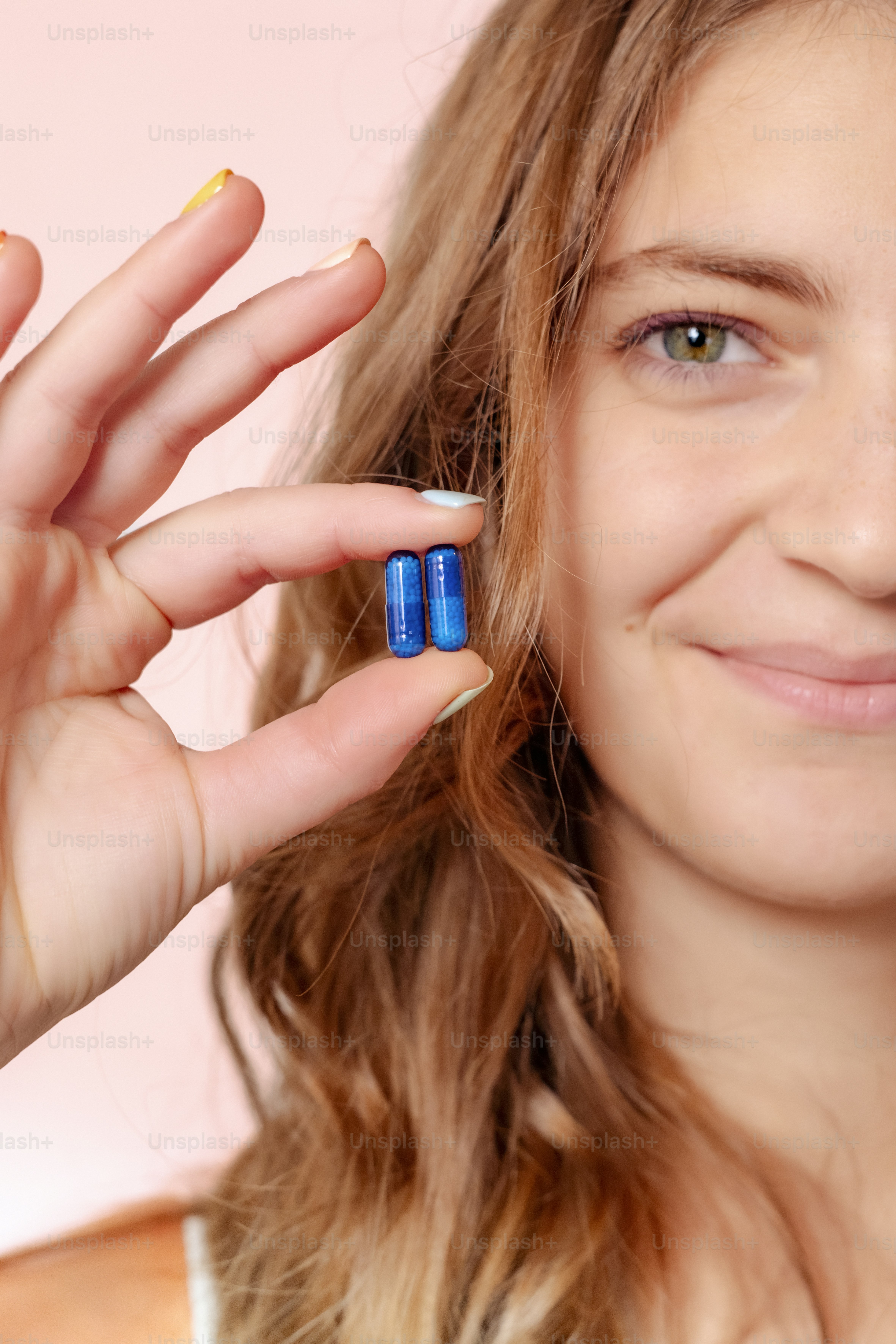 Une femme tenant deux pilules en forme de pilule dans sa main