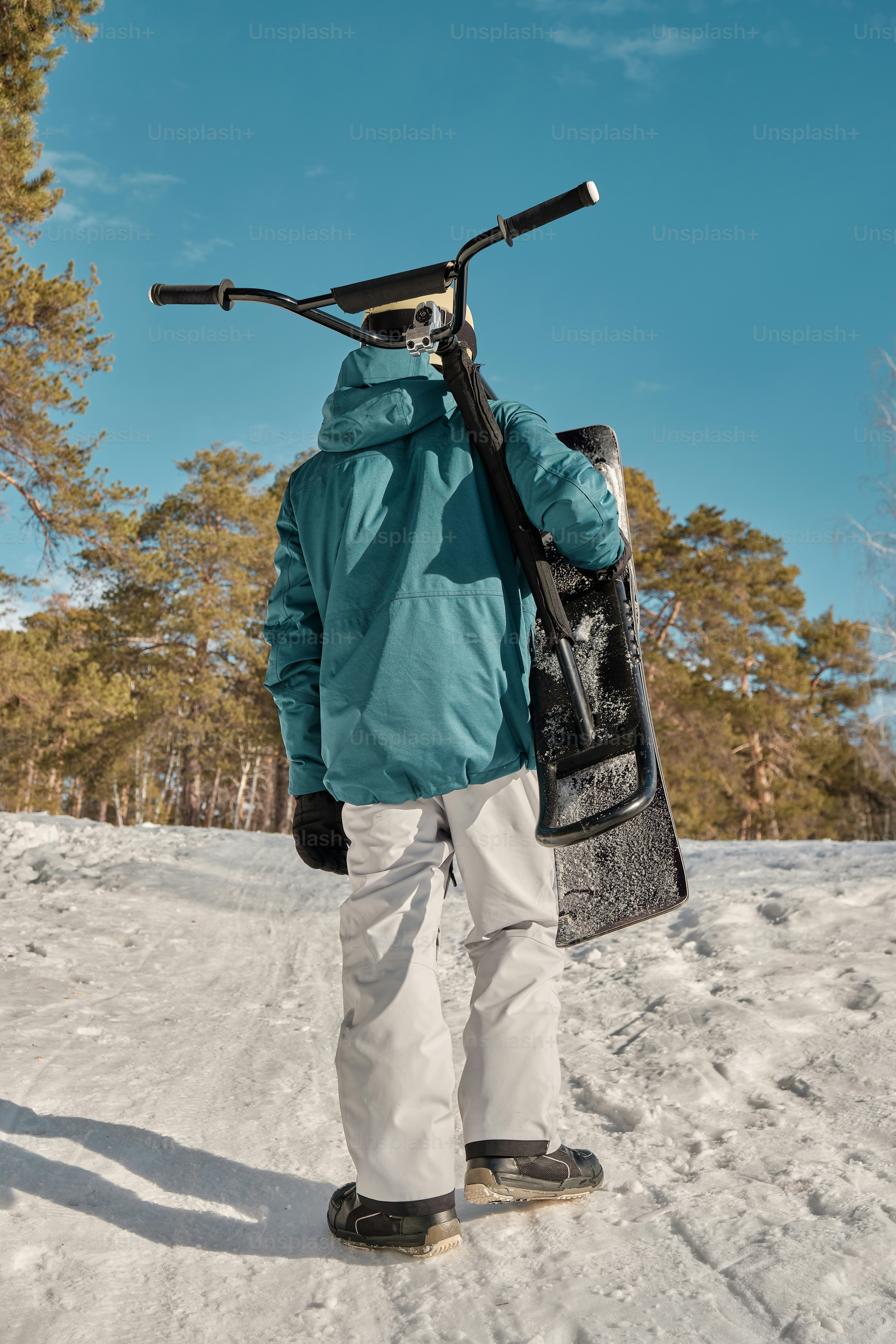 A person standing in the snow with a snowboard on their back