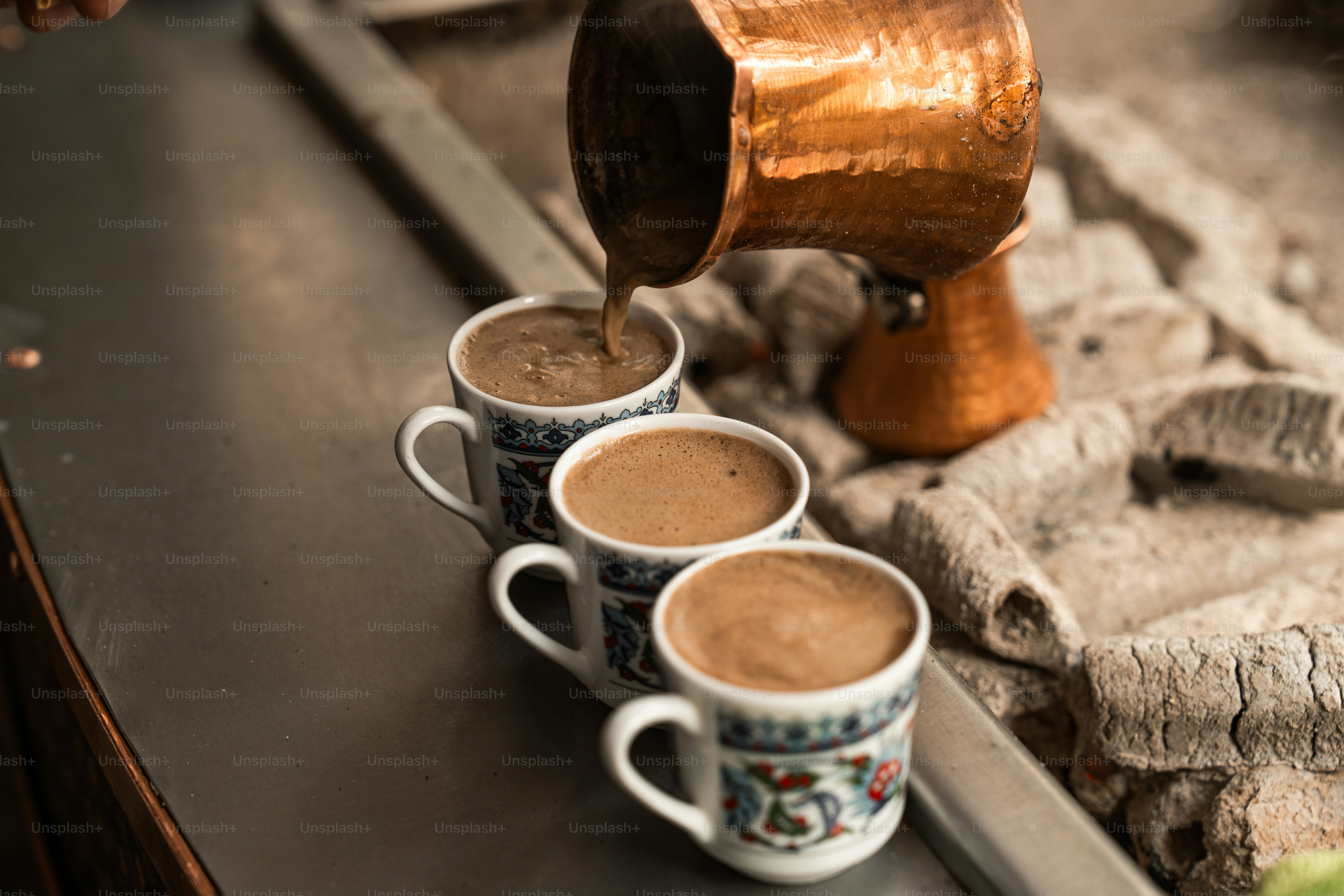 Three cups of coffee being poured into them