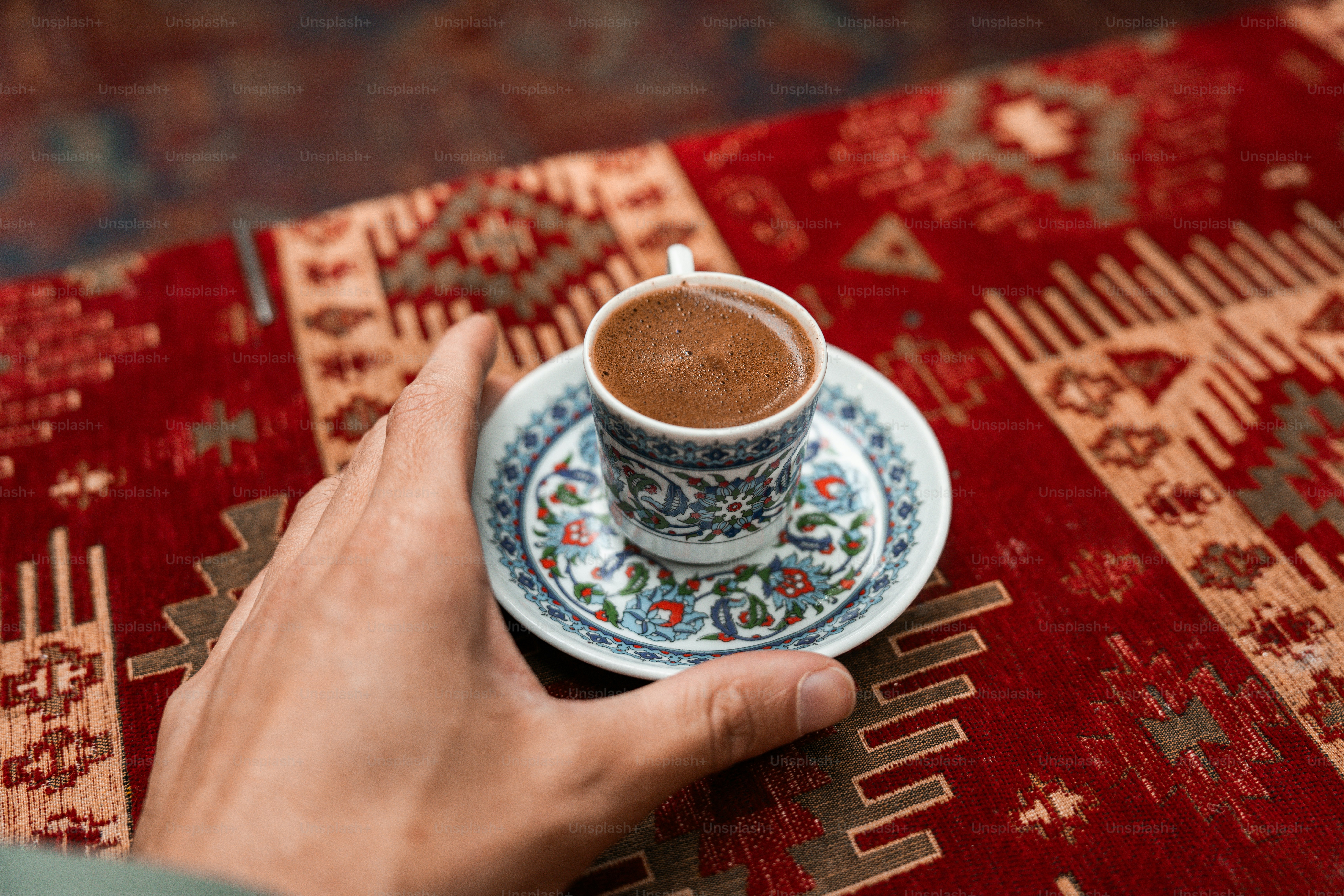 A person holding a cup of coffee on top of a rug