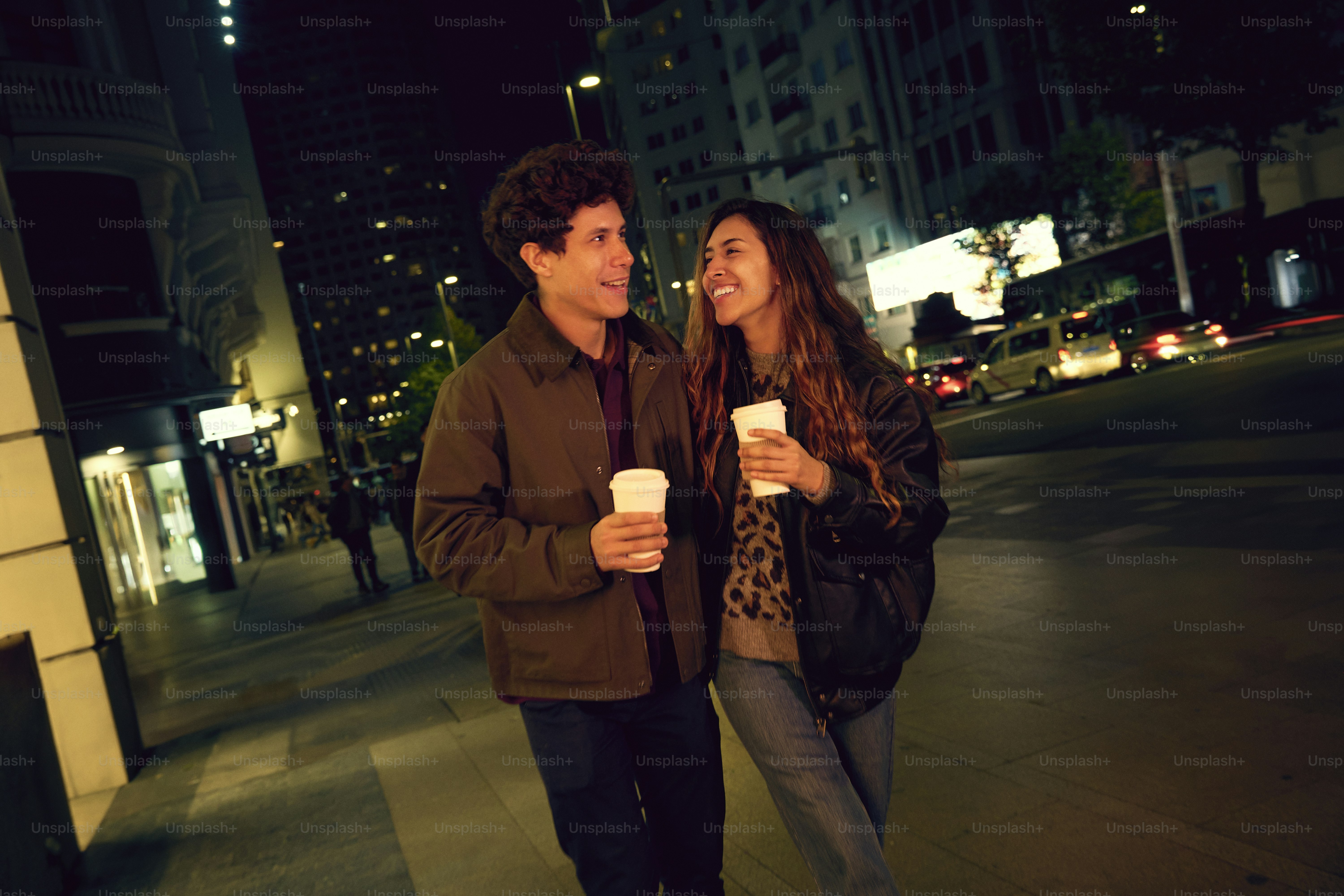 A man and a woman walking down a street at night photo – Couple Image ...