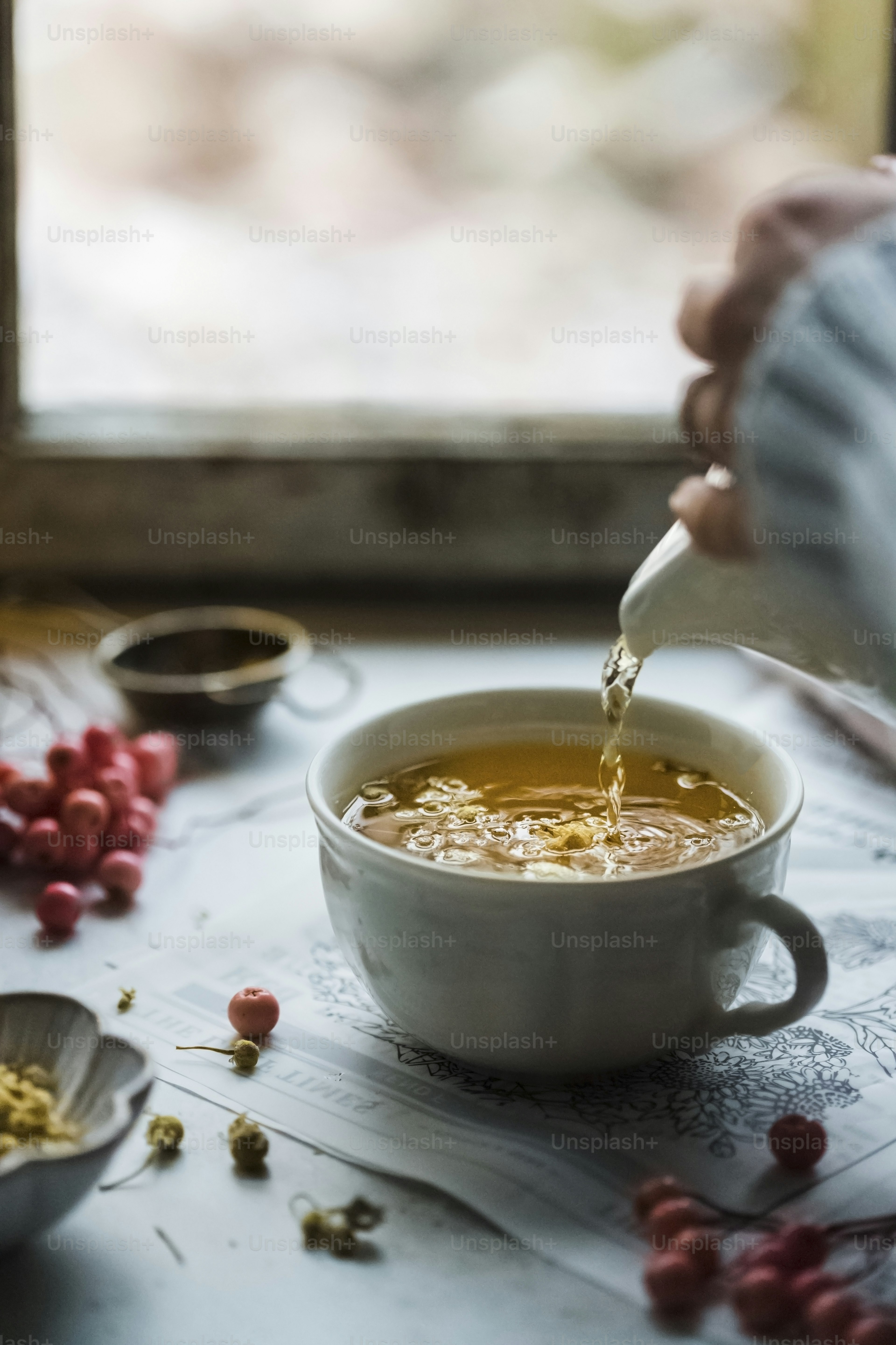A person pouring a cup of tea into a bowl