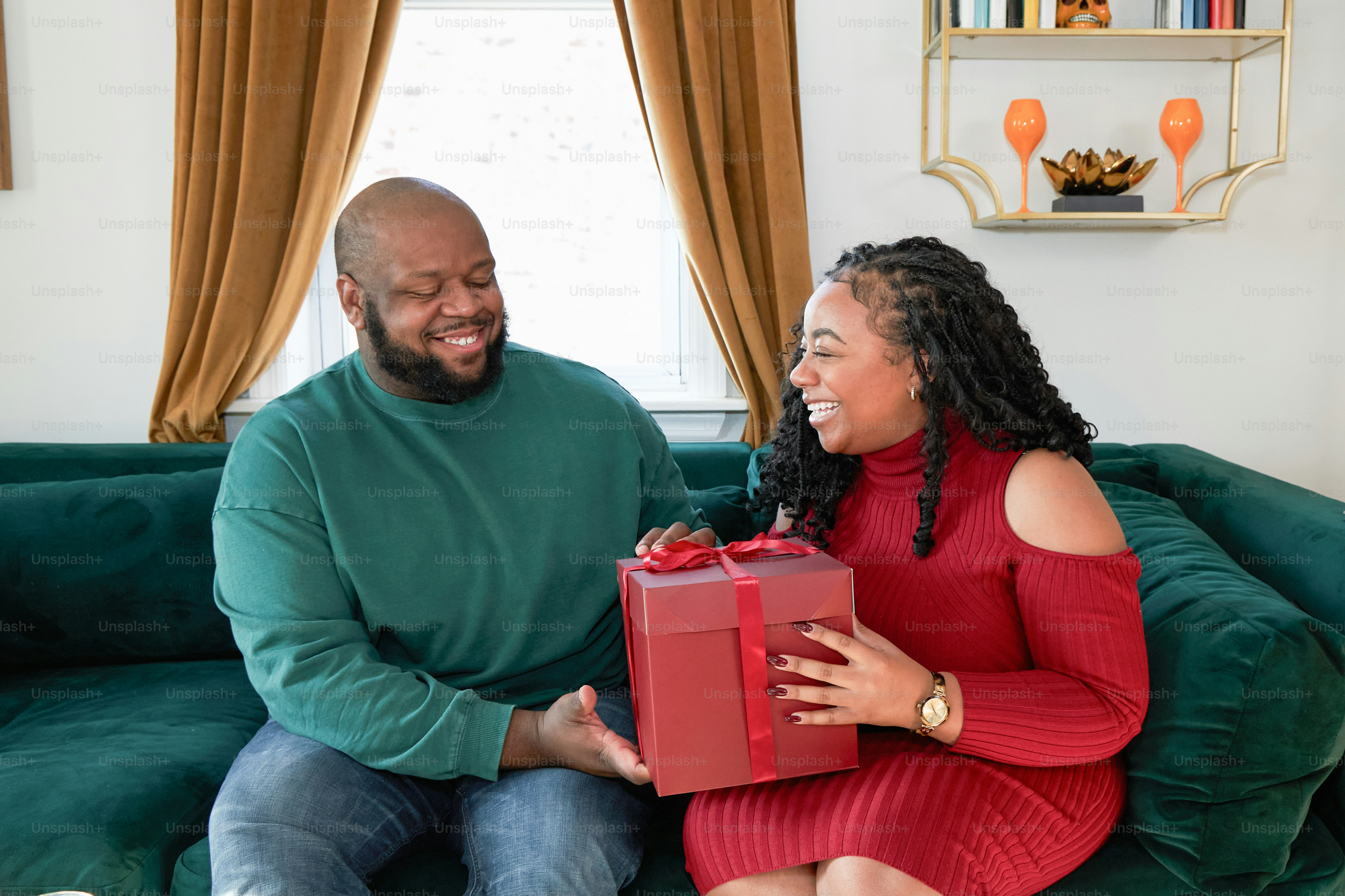 A man and woman sitting on a couch holding a present