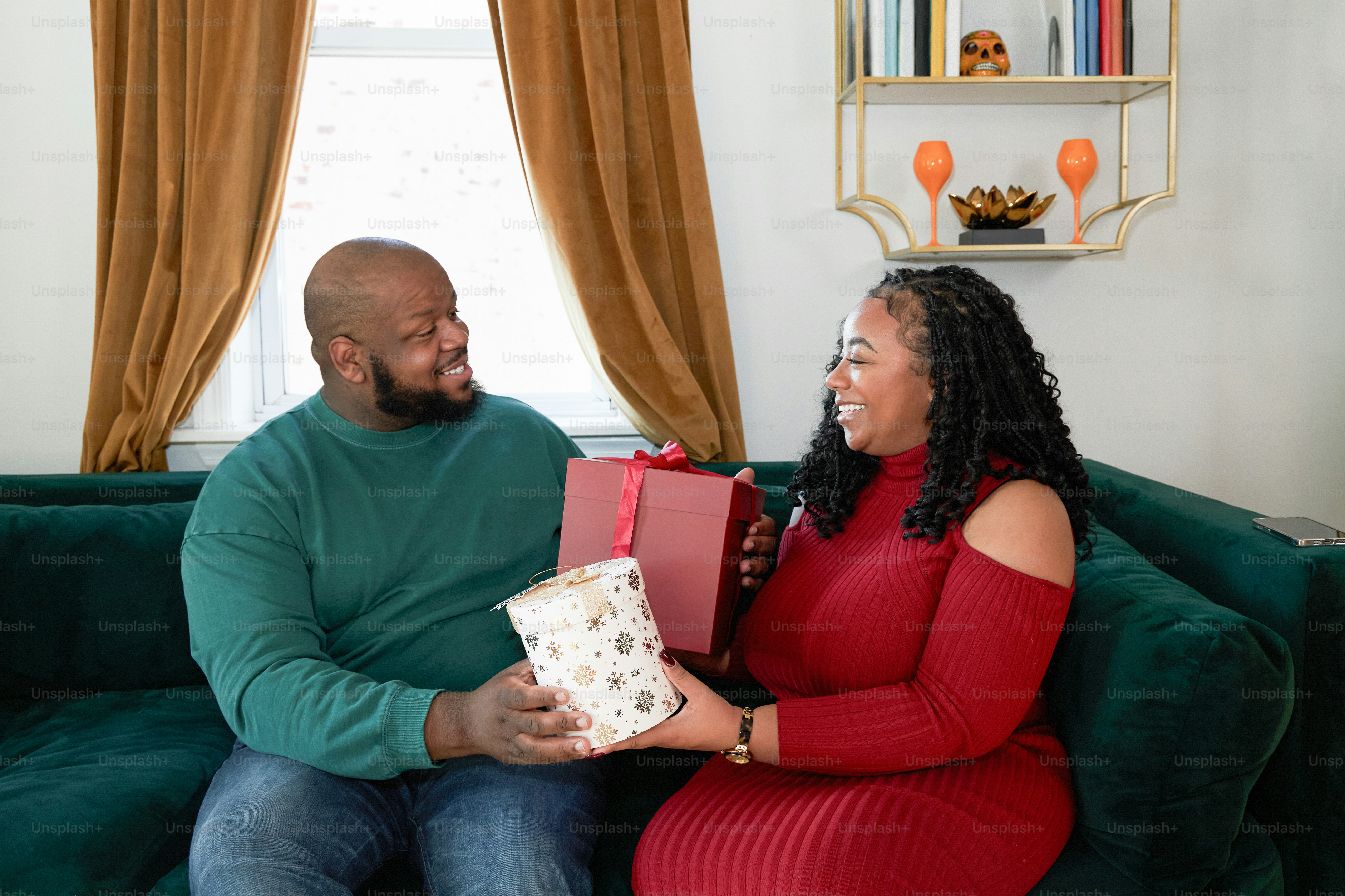 A man and woman sitting on a couch holding presents