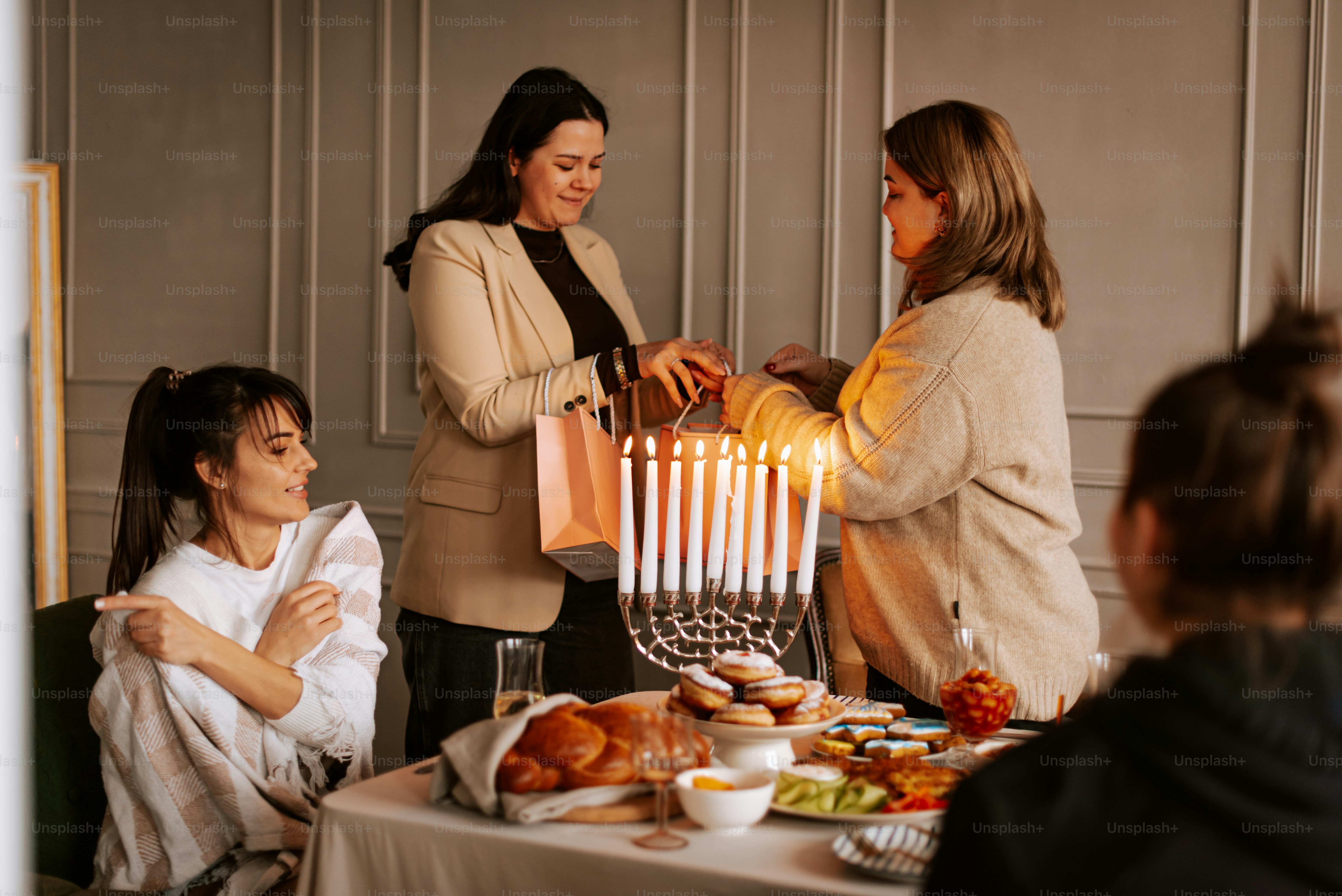 Un gruppo di donne in piedi intorno a un tavolo con una menora di hanukkah