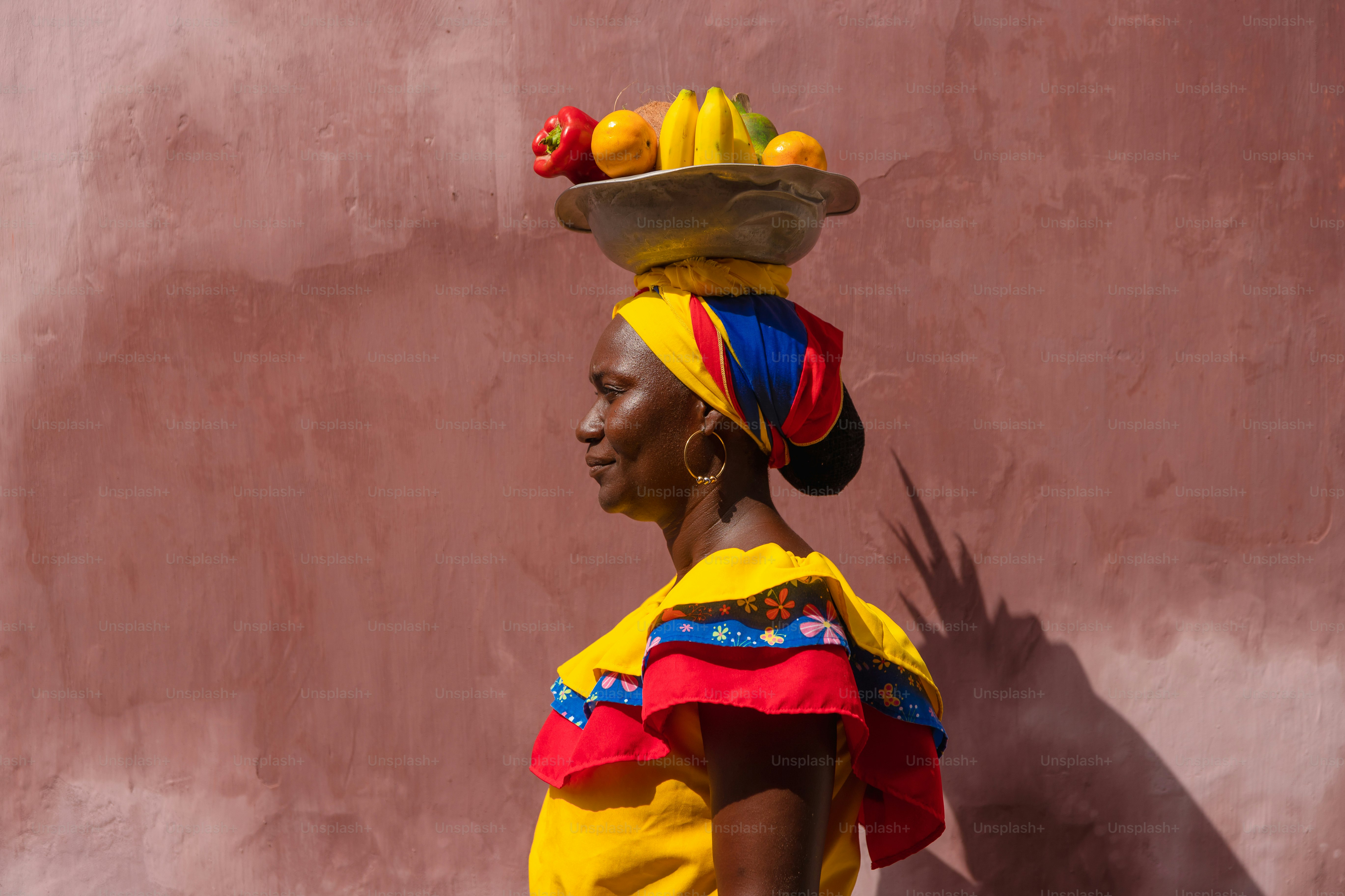 A woman carrying a tray of fruit on her head