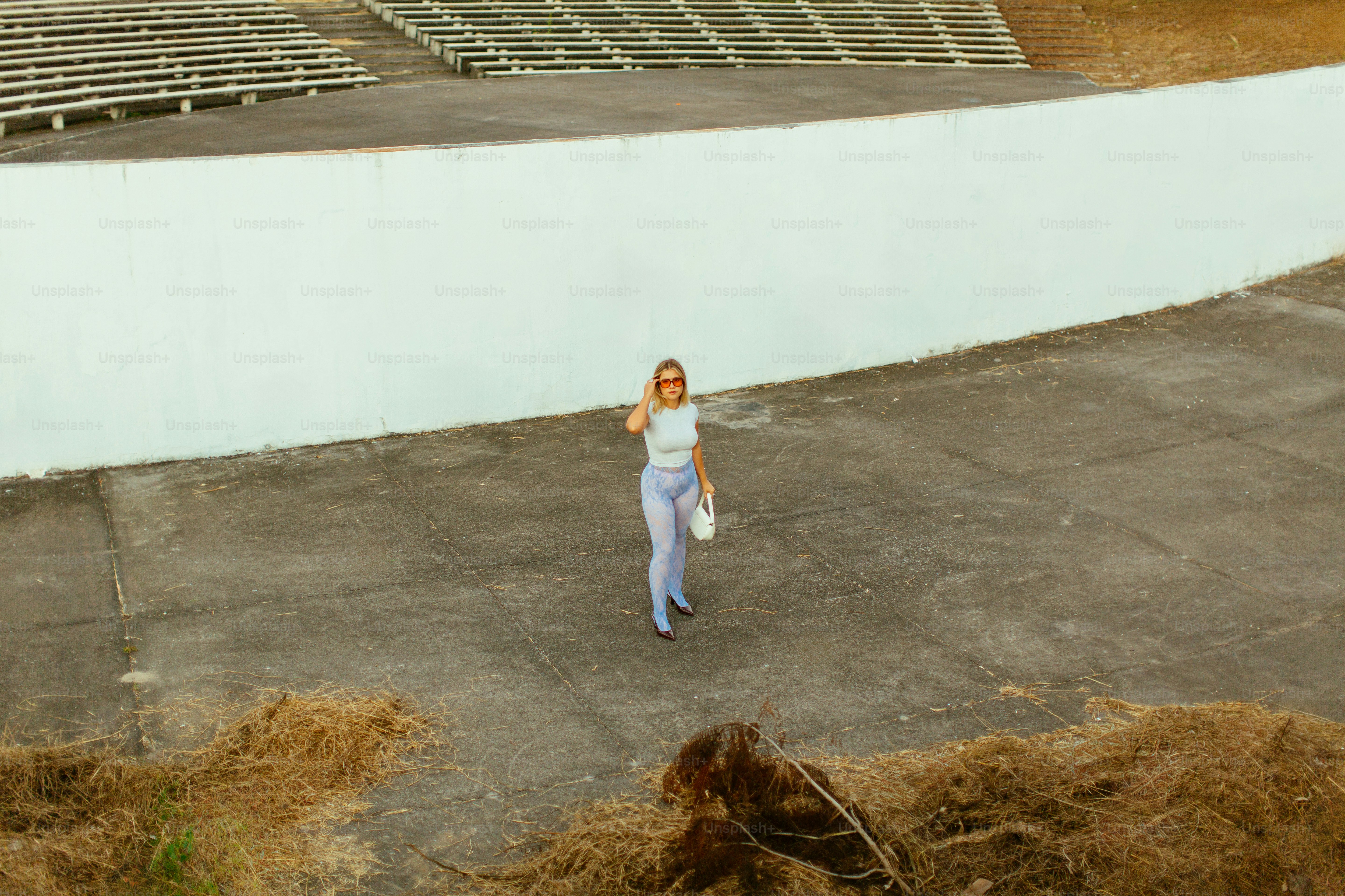 A woman standing in a field next to a bunch of hay
