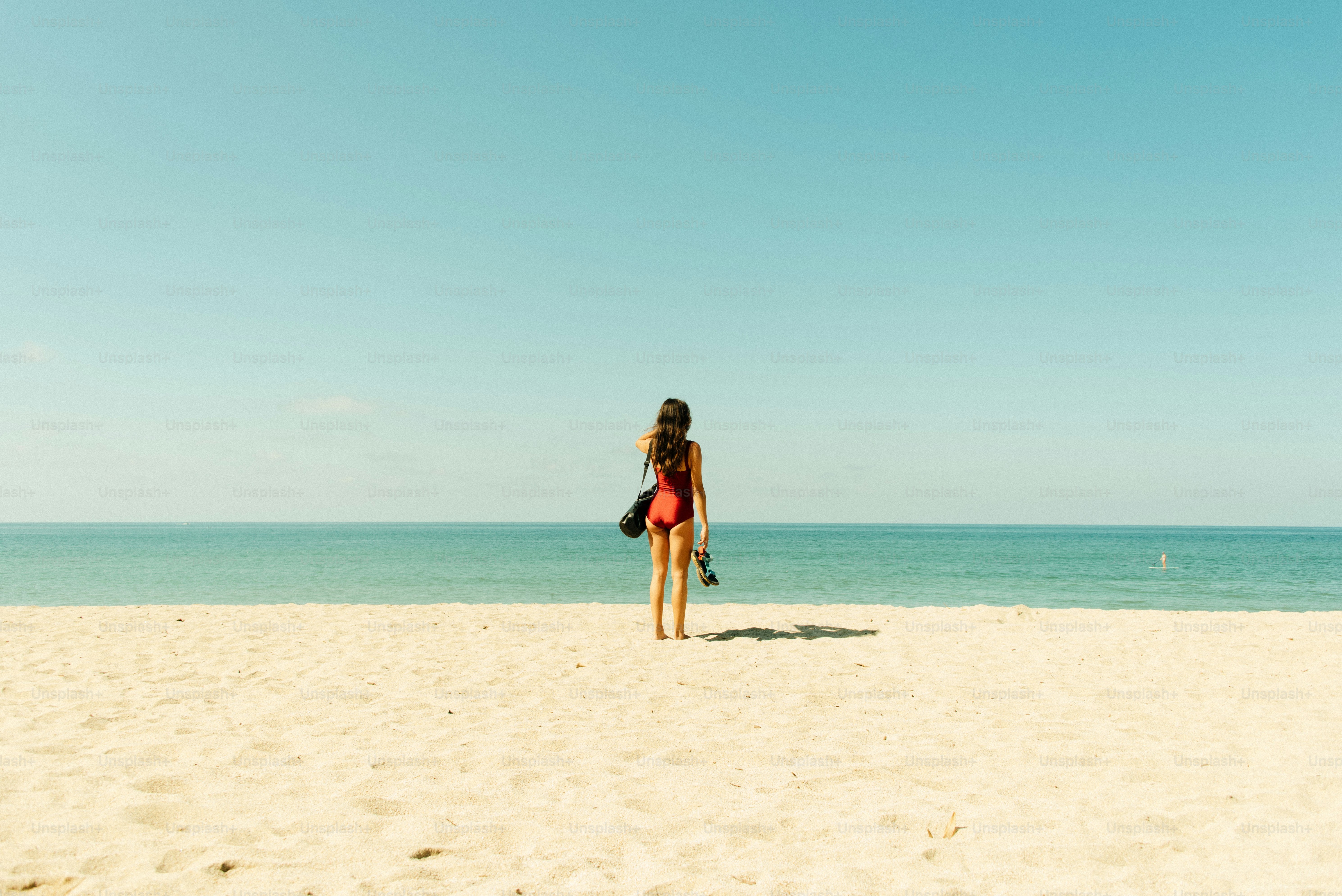 A woman standing on a beach next to the ocean