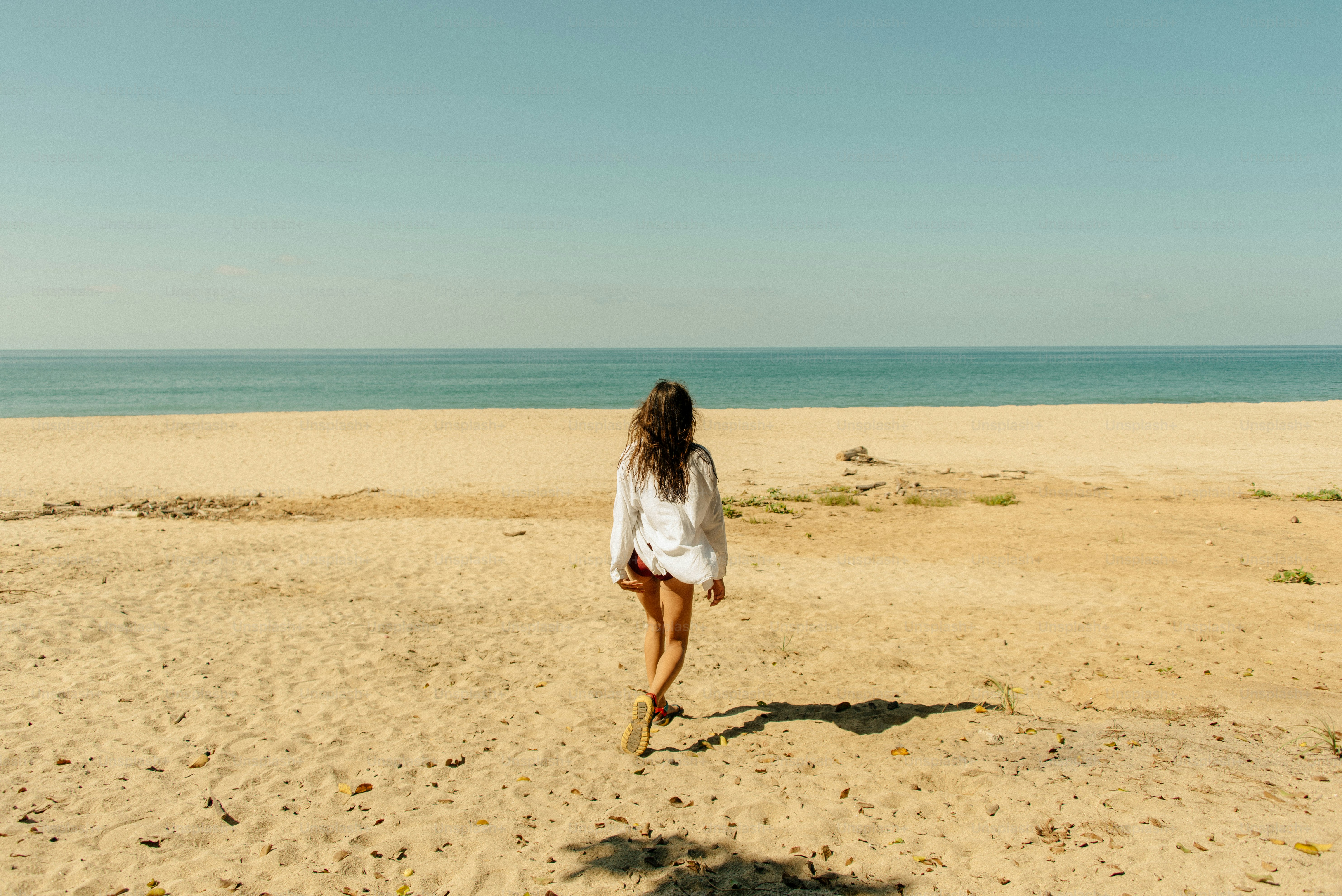 Una donna che cammina su una spiaggia sabbiosa vicino all'oceano