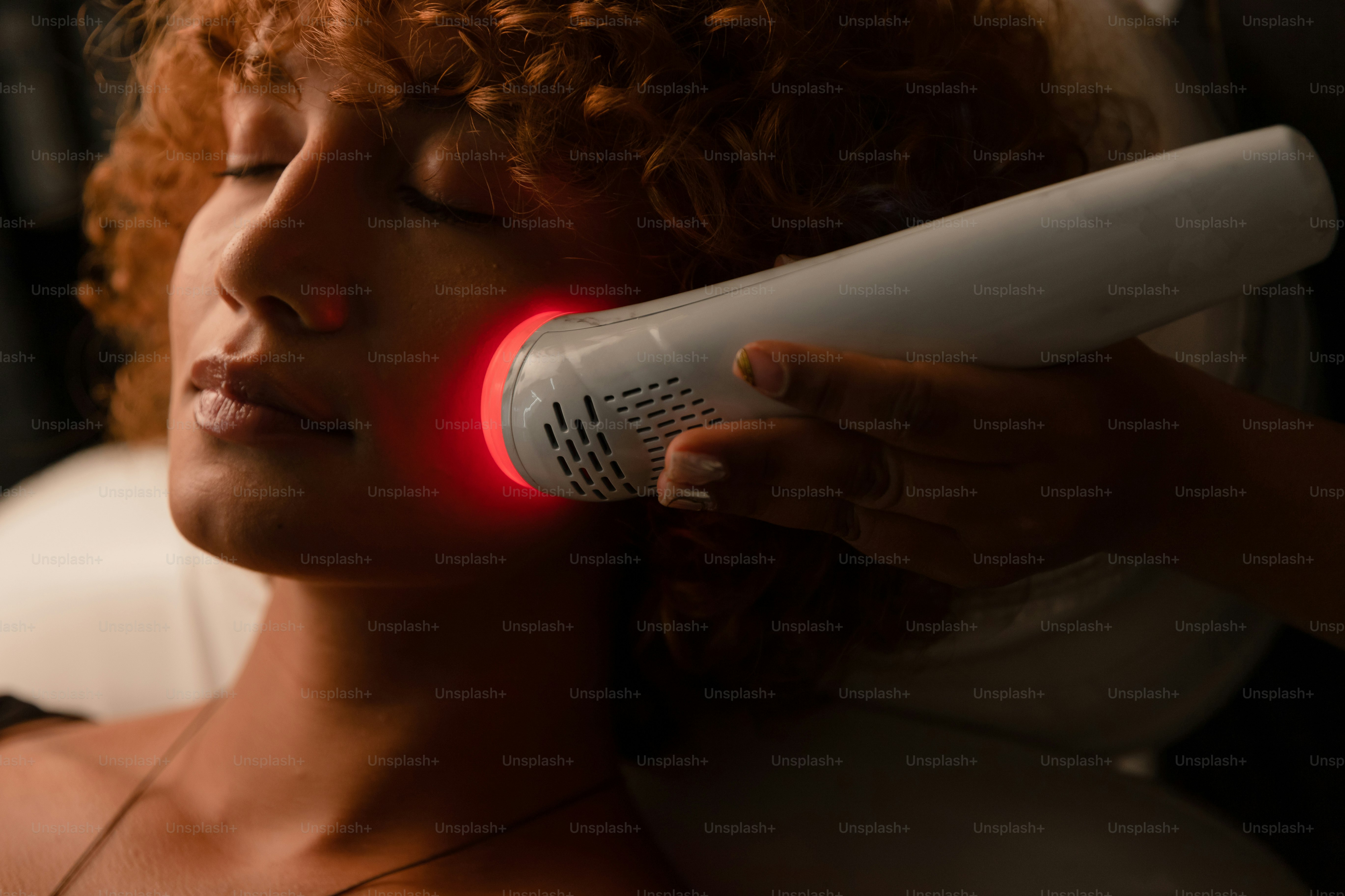 ヘアドライヤーを使いながらベッドに横たわる女性