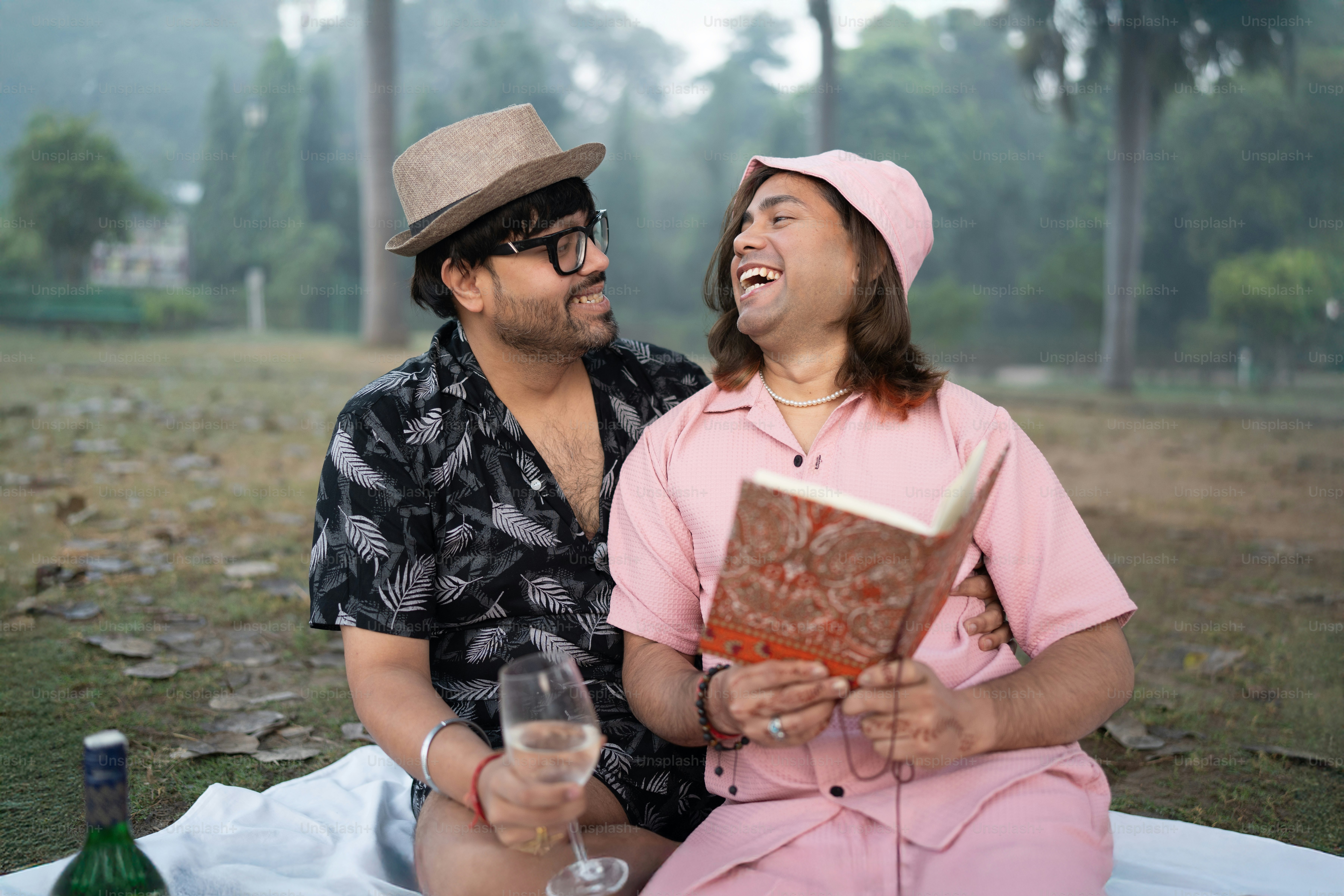 A man and a woman sitting on a blanket with a book