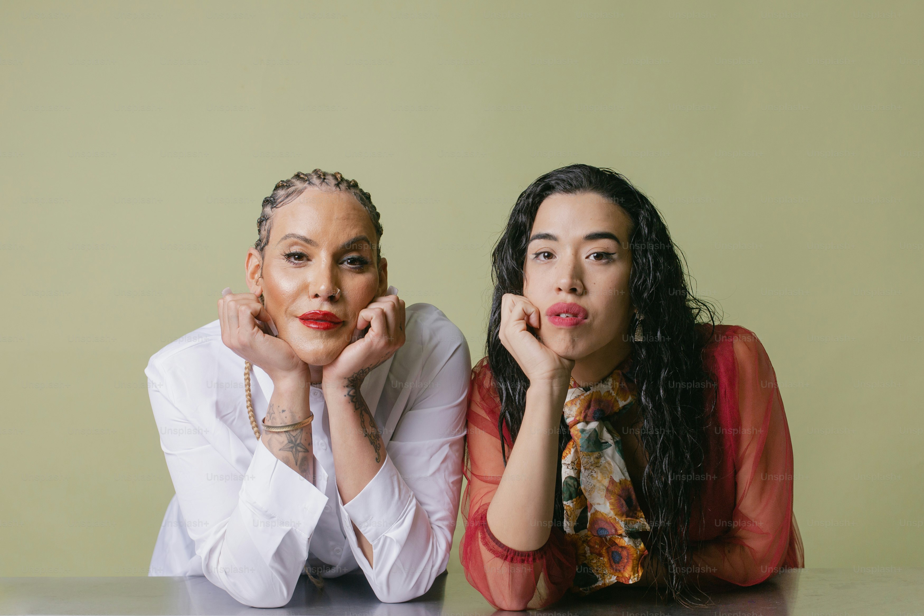 Two women sitting at a table with their hands on their chins