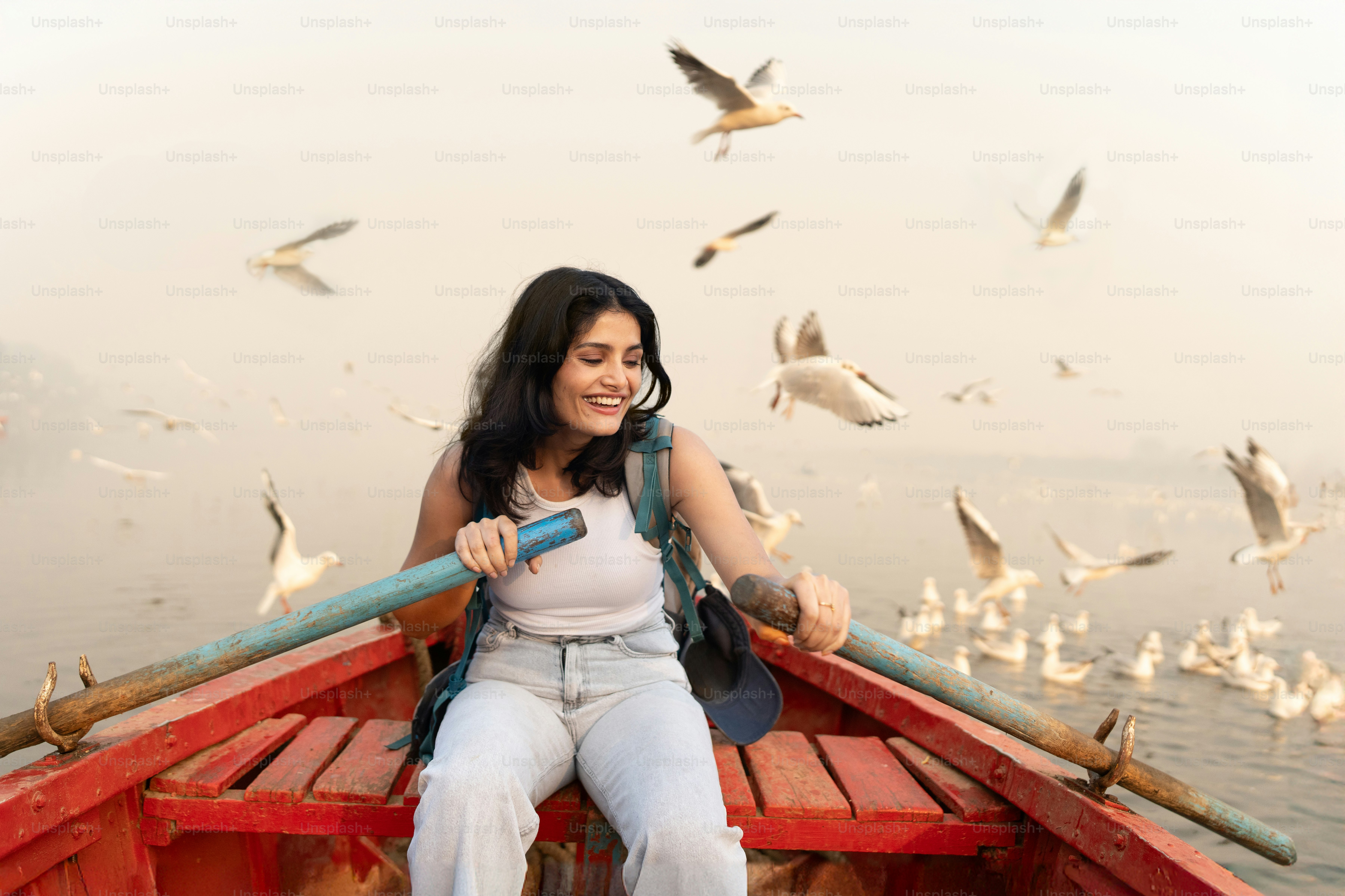 Una mujer sentada en un bote rodeada de gaviotas