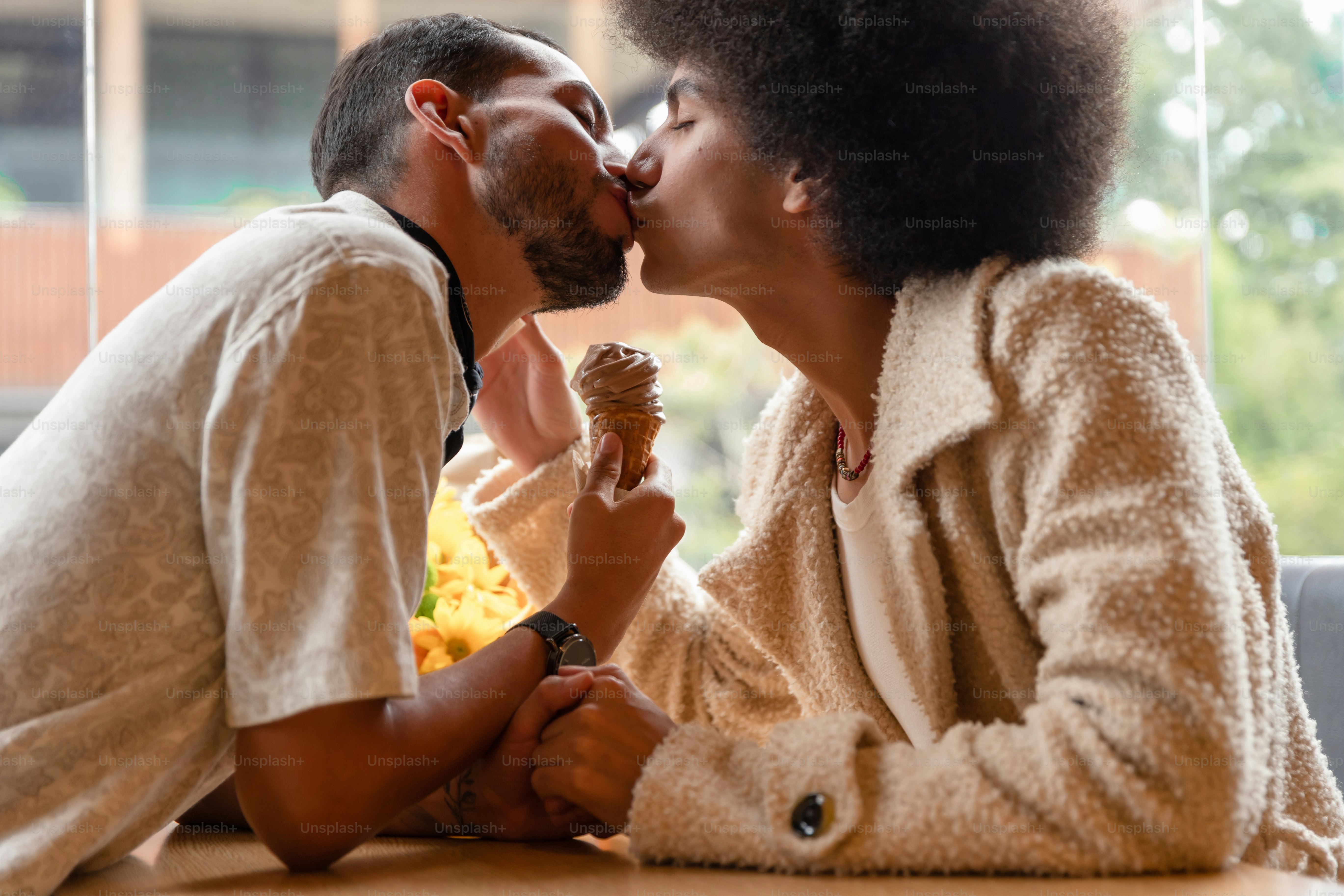 A man and a woman kissing while sitting at a table