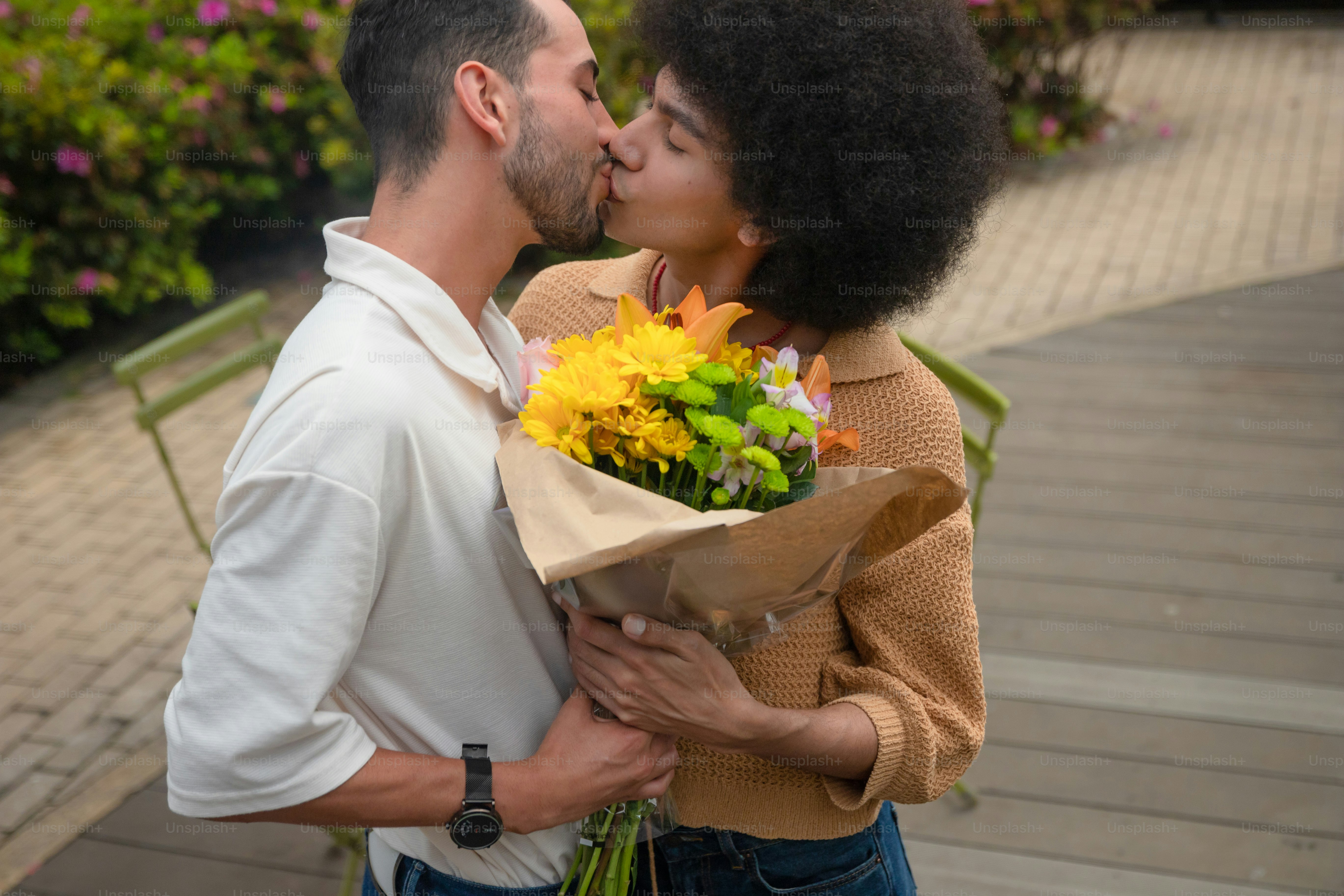 A man kissing a woman while holding a bouquet of flowers