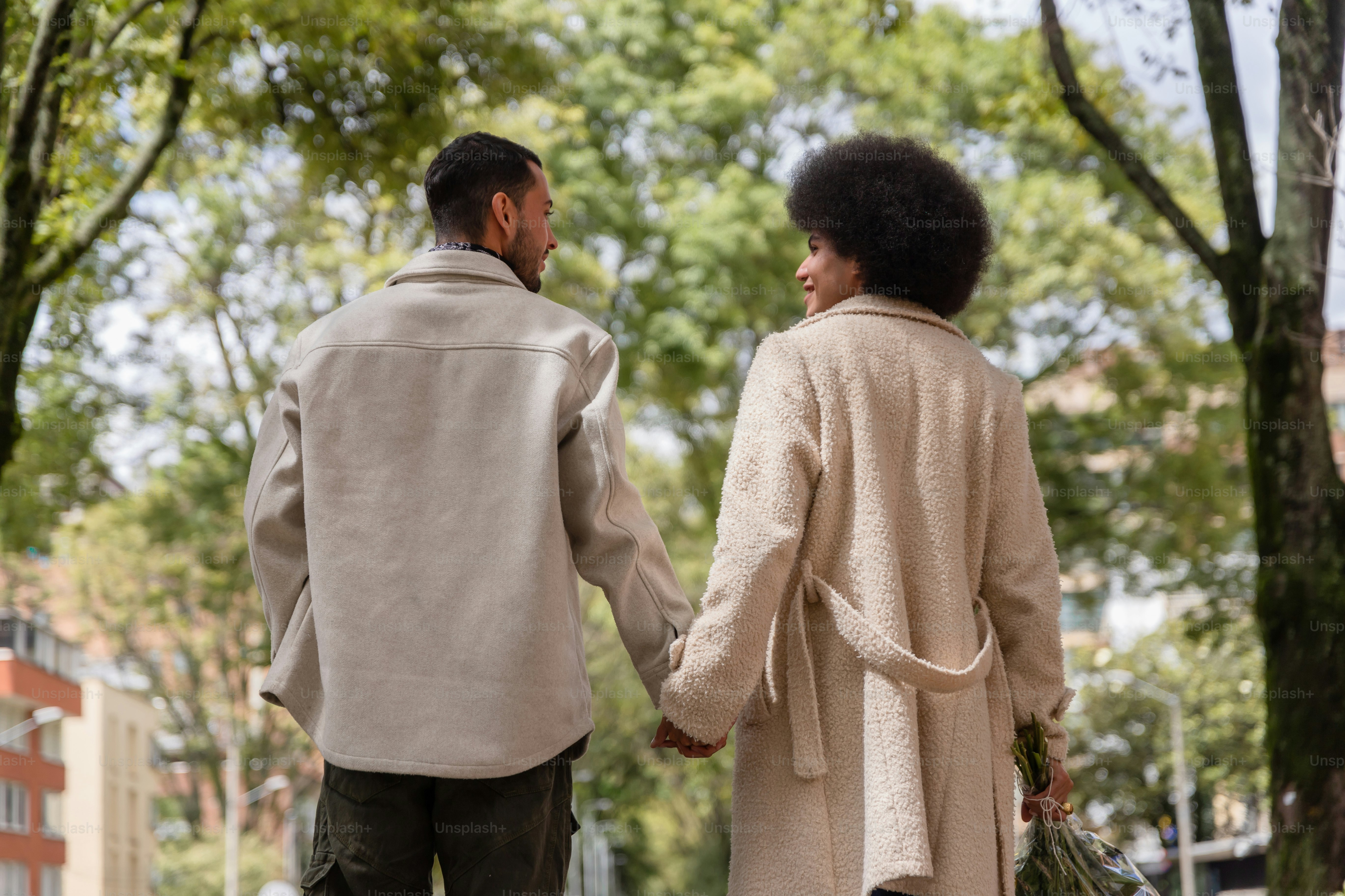A man and a woman walking down a sidewalk holding hands